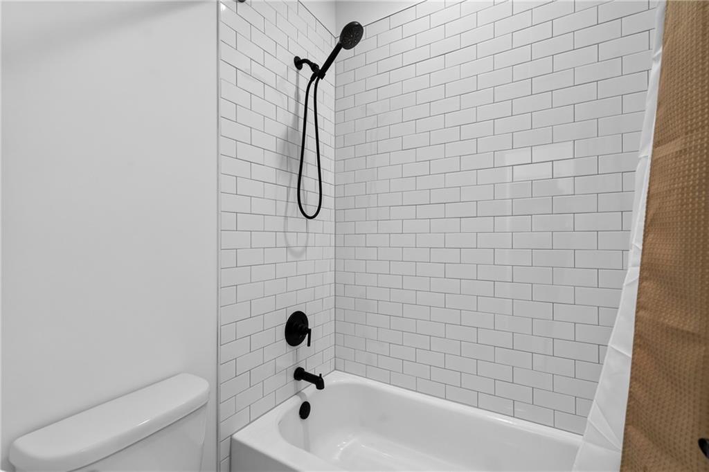Bathroom tub and shower with white subway tile and matte black fixtures.