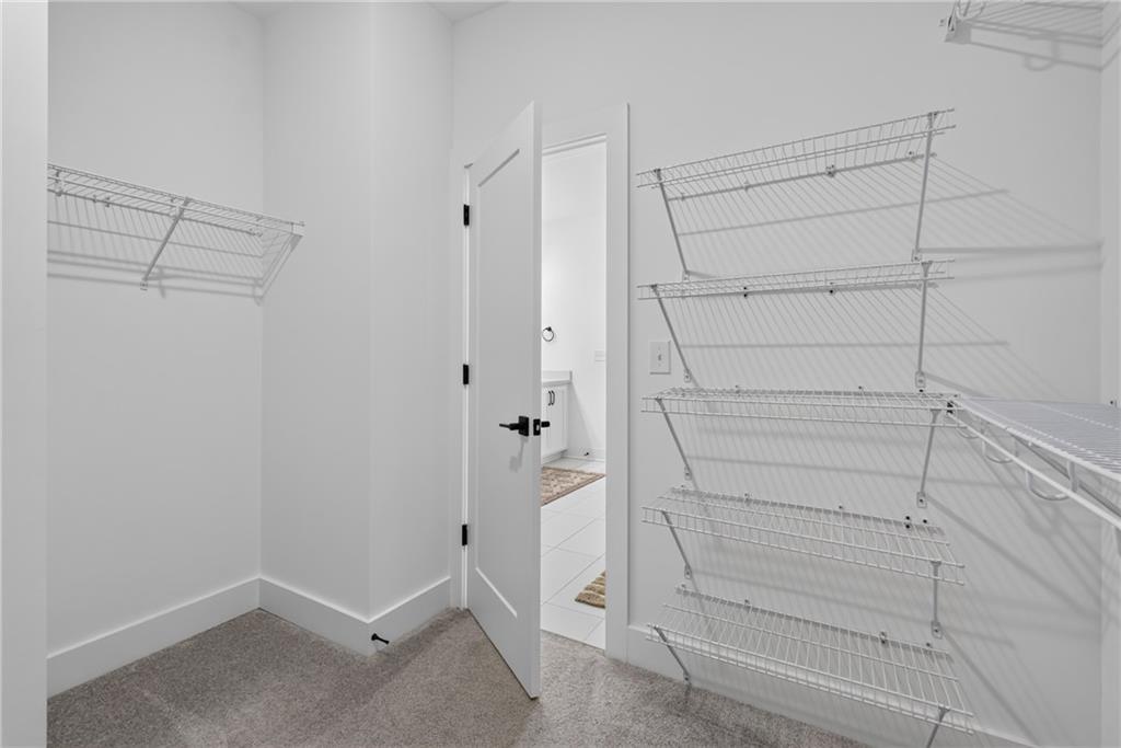 Walk-in closet with white wire shelving and an open door to a tiled bathroom.