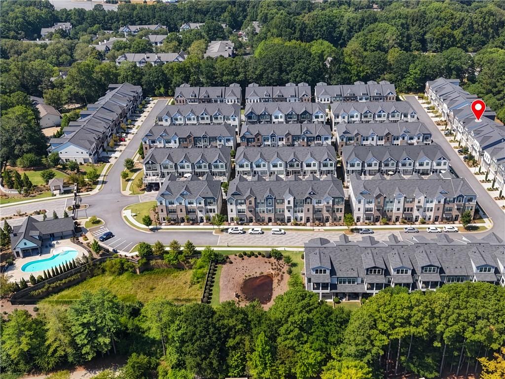 Aerial view of a townhome community with a swimming pool and surrounding trees.