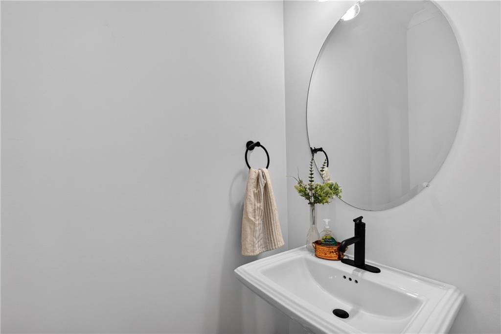 Bathroom sink with black faucet, oval mirror, and towel ring.