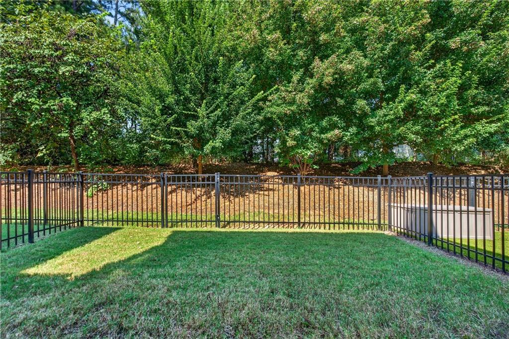 Fenced backyard with a grassy lawn and mature trees.