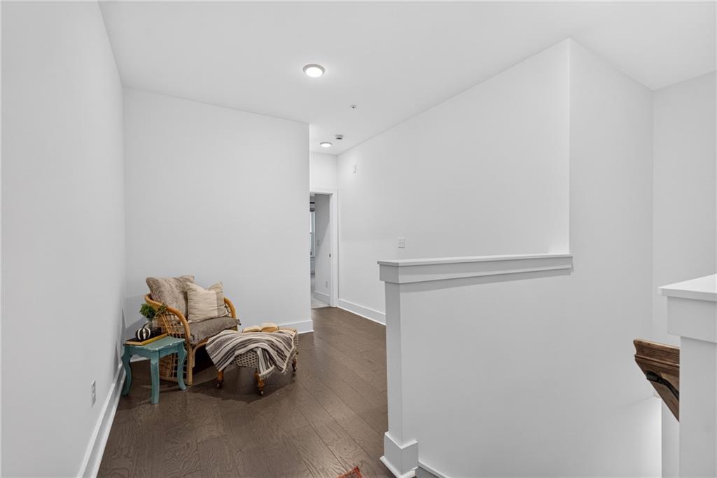 Hallway landing with a wicker chair, small side table, and dark wood flooring.