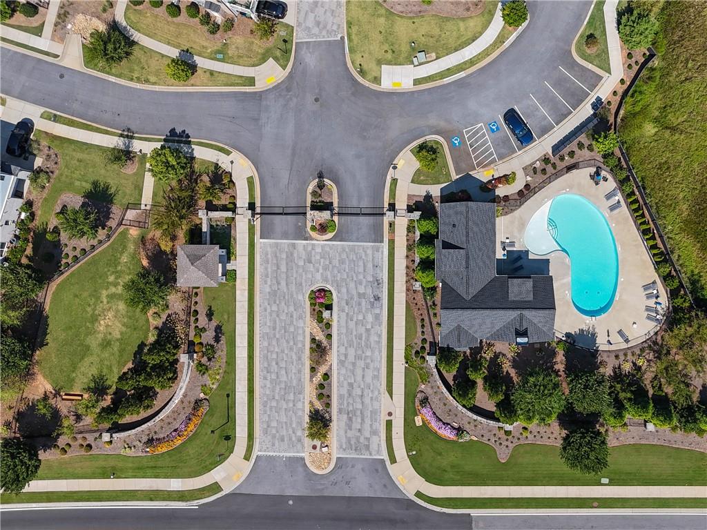 Aerial view of a landscaped neighborhood entrance beside a community pool.