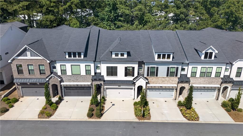 Aerial view of attached townhomes with garages, varied gables, and landscaped driveways.