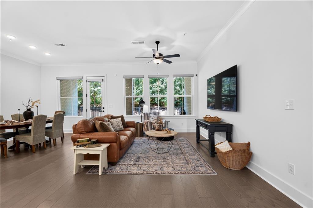 Living room with a leather sofa, patterned rug, ceiling fan, and adjoining dining area.