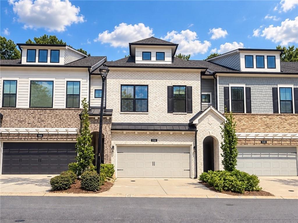 Townhouse exterior with a pale brick facade, black-trimmed windows, and an arched entryway.