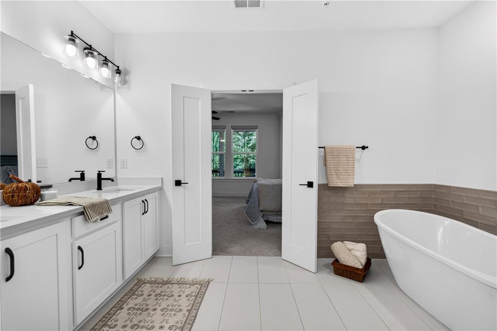 Bathroom with double vanity and freestanding soaking tub, opening to a bedroom.