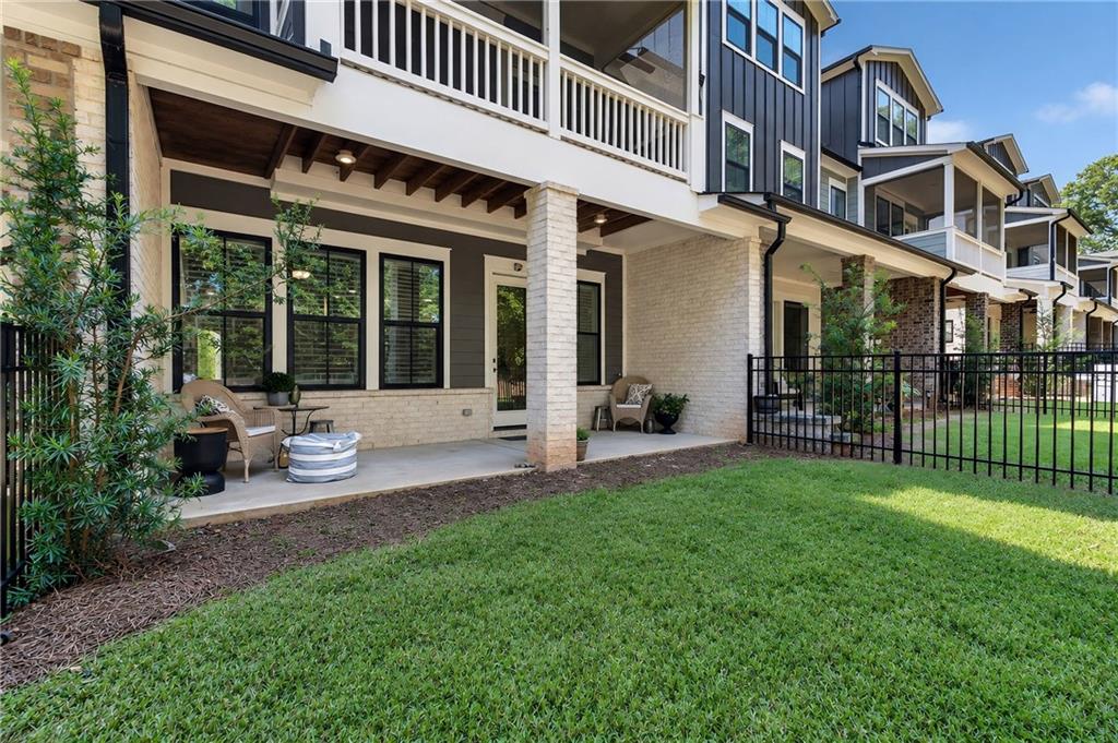Townhome patio with seating, white brick columns, and a fenced lawn.