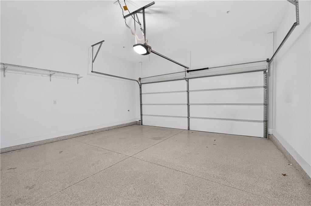 Empty garage with a speckled floor, overhead storage rails, and a closed sectional door.