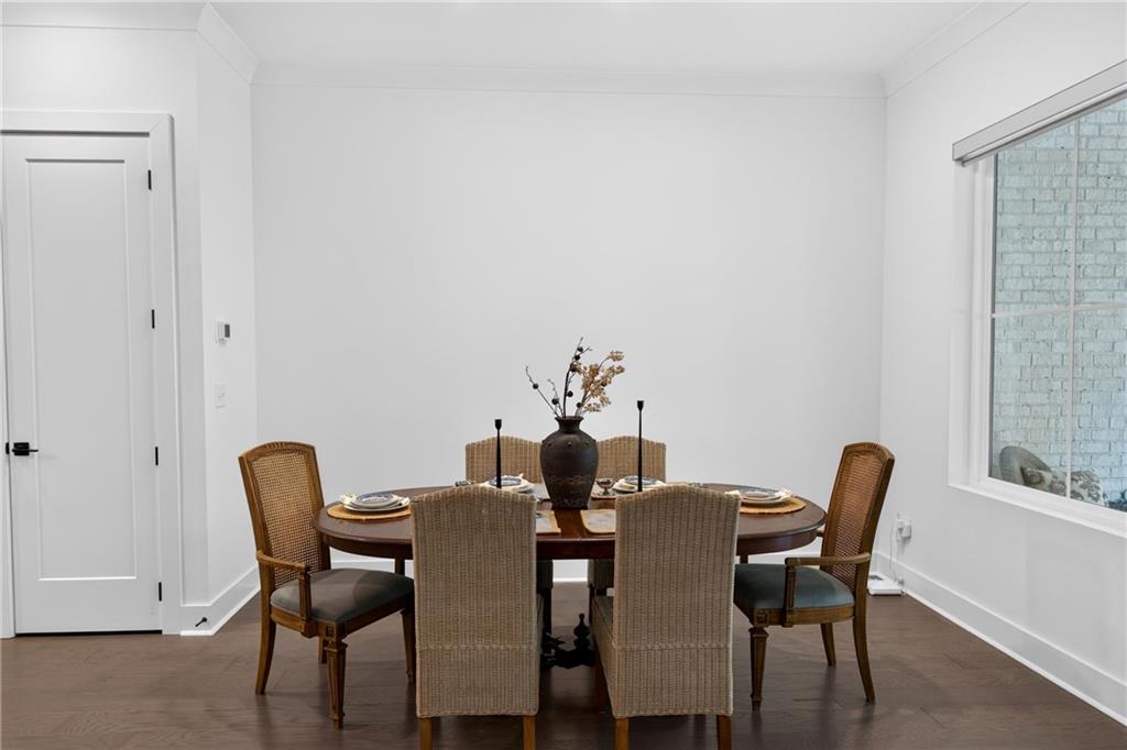Dining room with a set oval table, woven chairs, and dark hardwood floors.