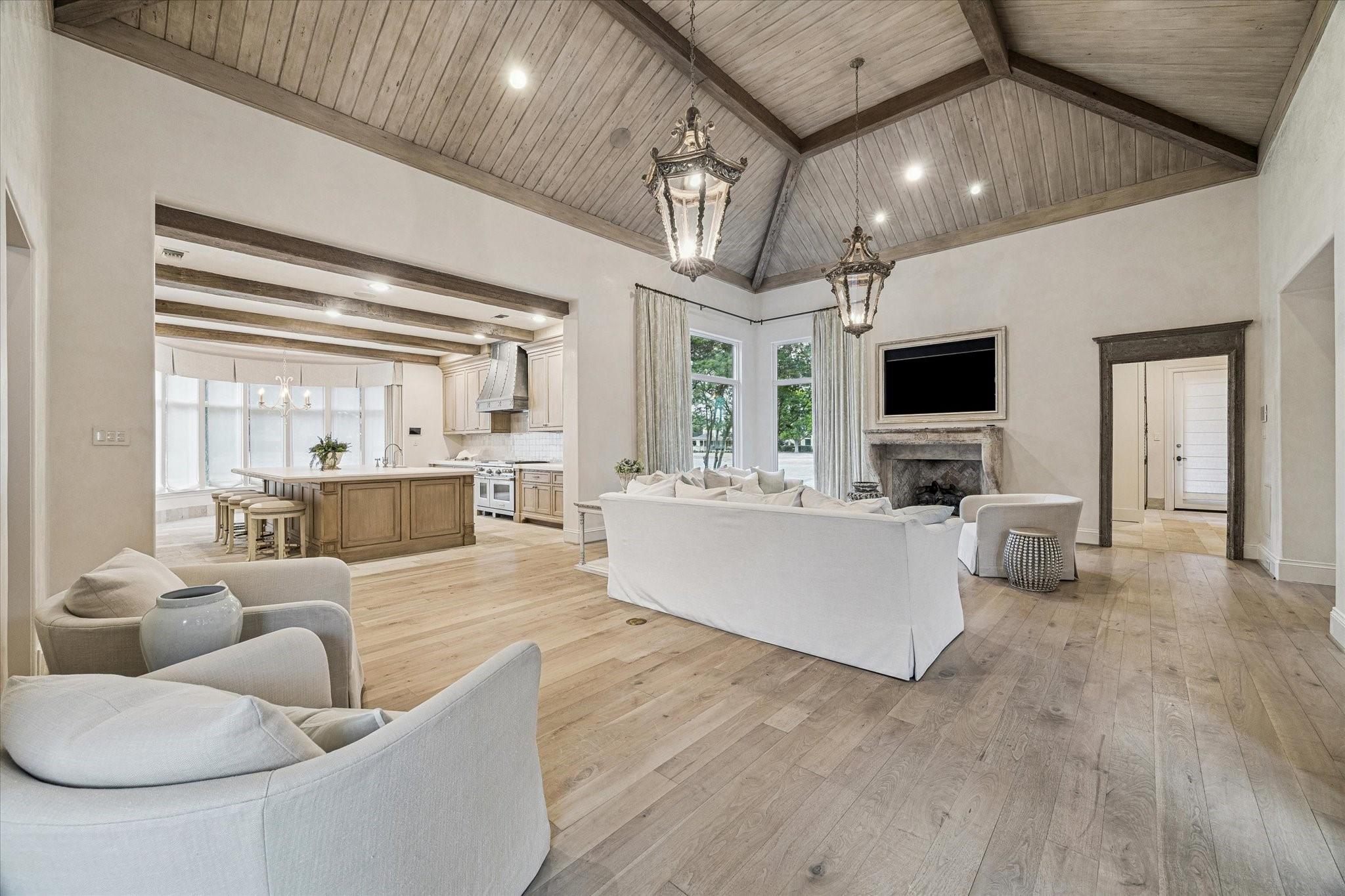 Open living room and kitchen with vaulted wood ceiling, stone fireplace, and large island.