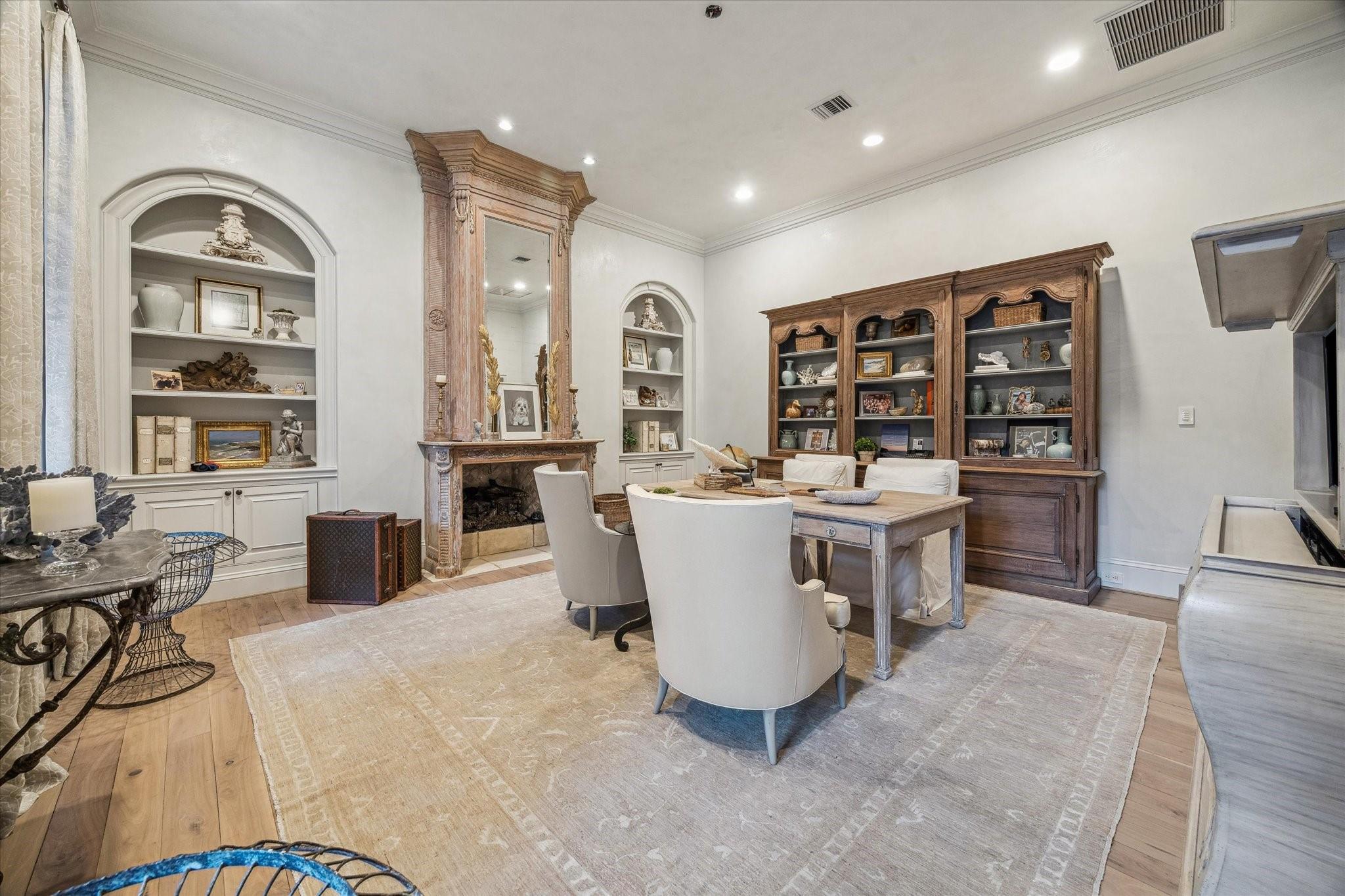 Dining room with a carved fireplace, built-in display shelves, and a light wood dining table.