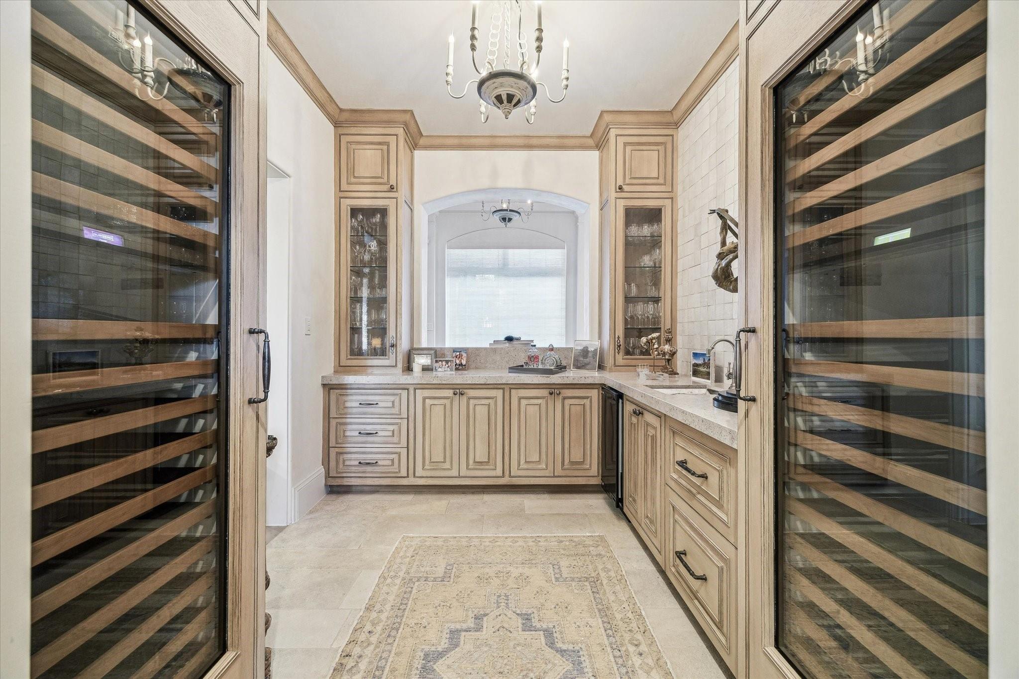 Wine room with twin glass-fronted wine refrigerators and light wood cabinetry.