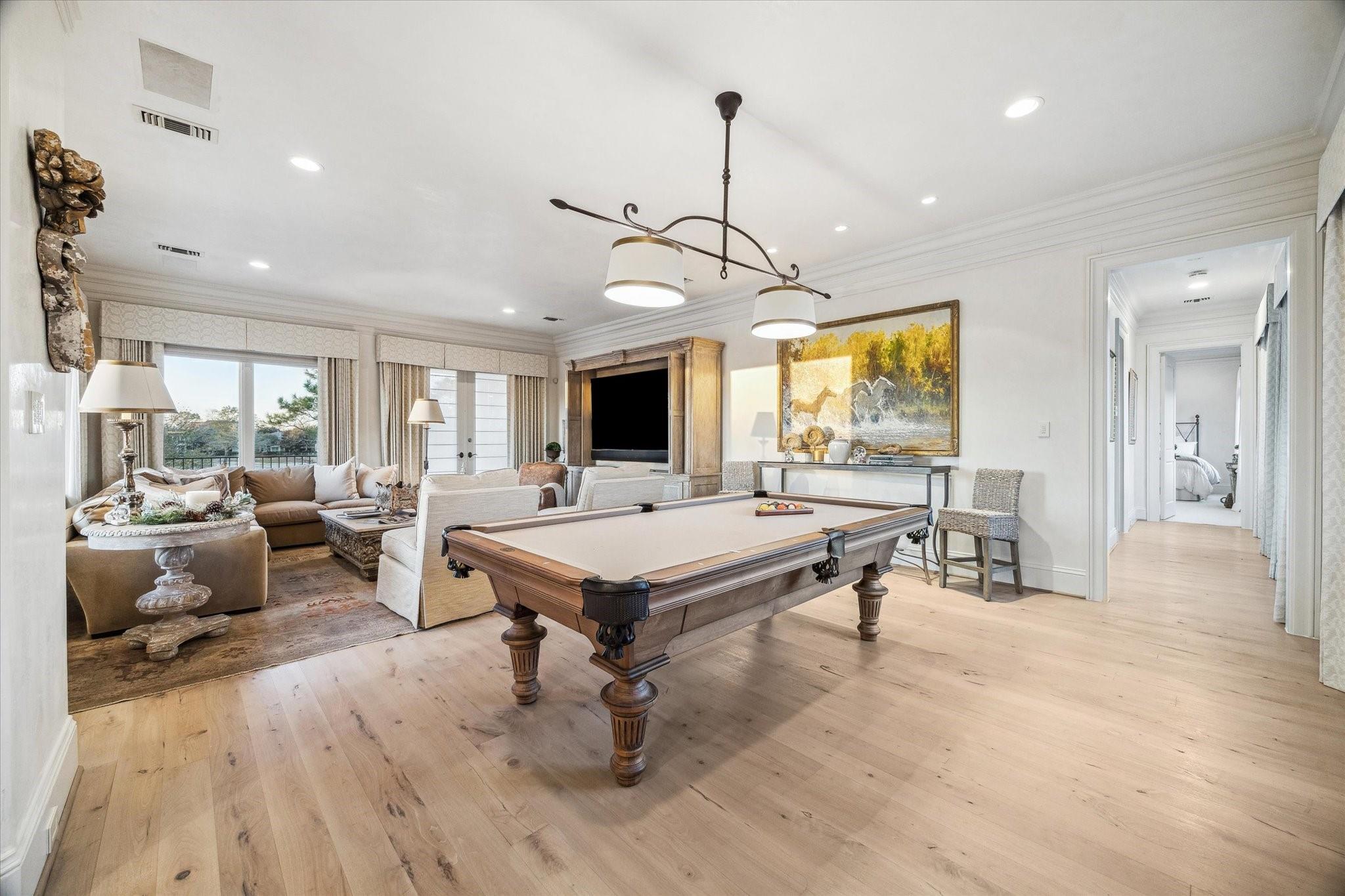 Game room with a pool table, adjoining sitting area, and large windows.