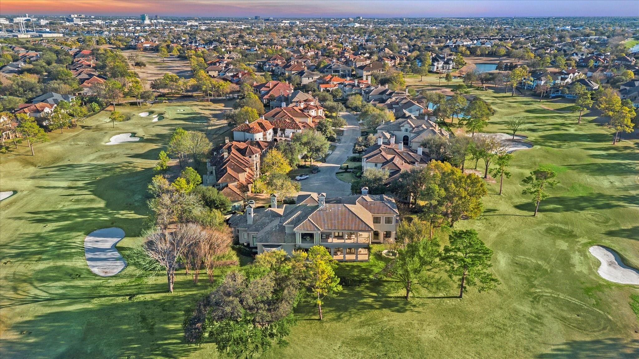 Aerial view of a home beside a golf course with sand bunkers and surrounding homes.