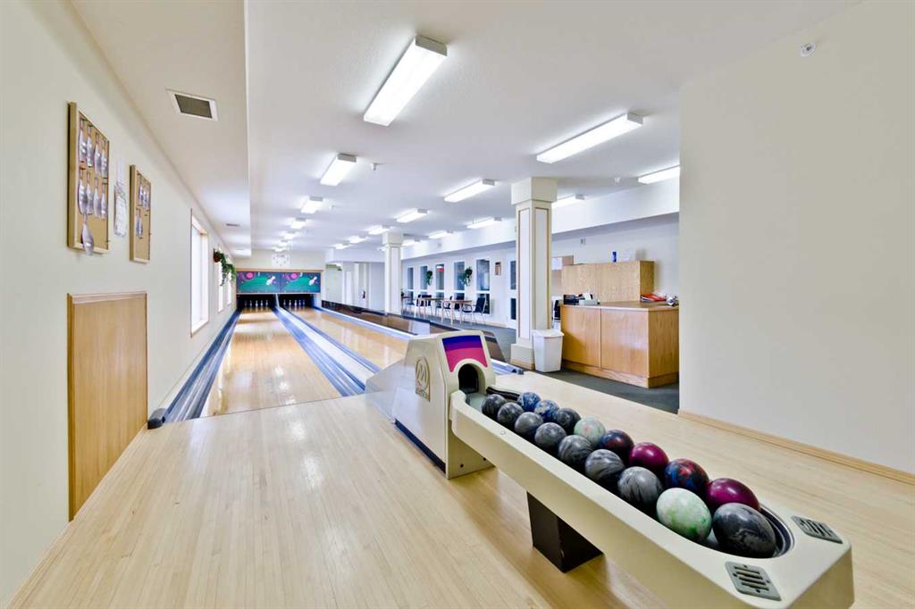 Indoor bowling alley with multiple lanes and a ball return filled with bowling balls.