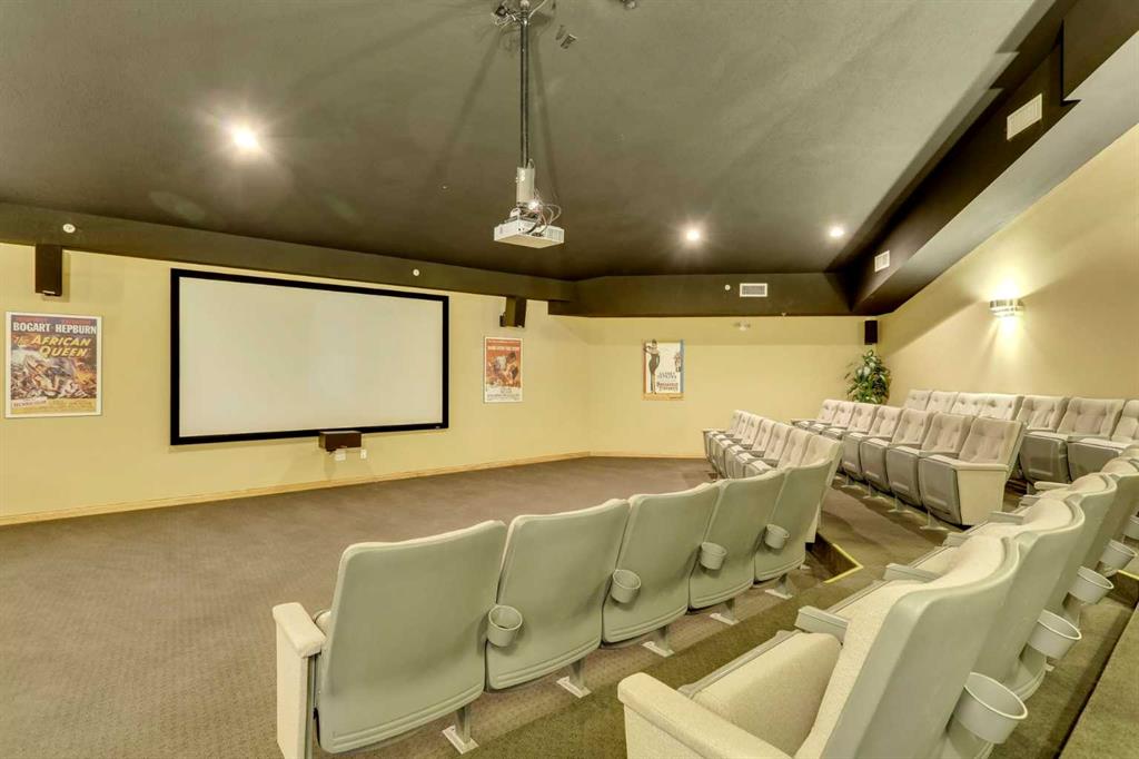 Home theater with tiered upholstered seating, a large projection screen, and ceiling-mounted projector.