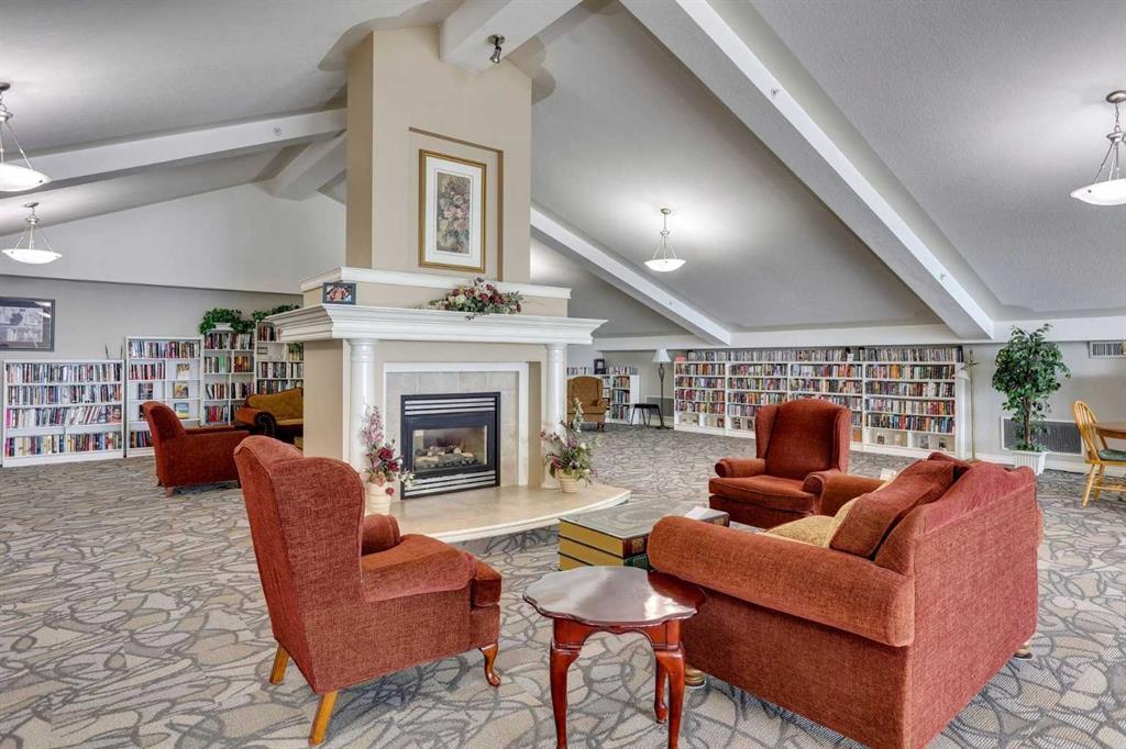 Shared library lounge with wall-to-wall bookshelves, red seating, and a central fireplace.
