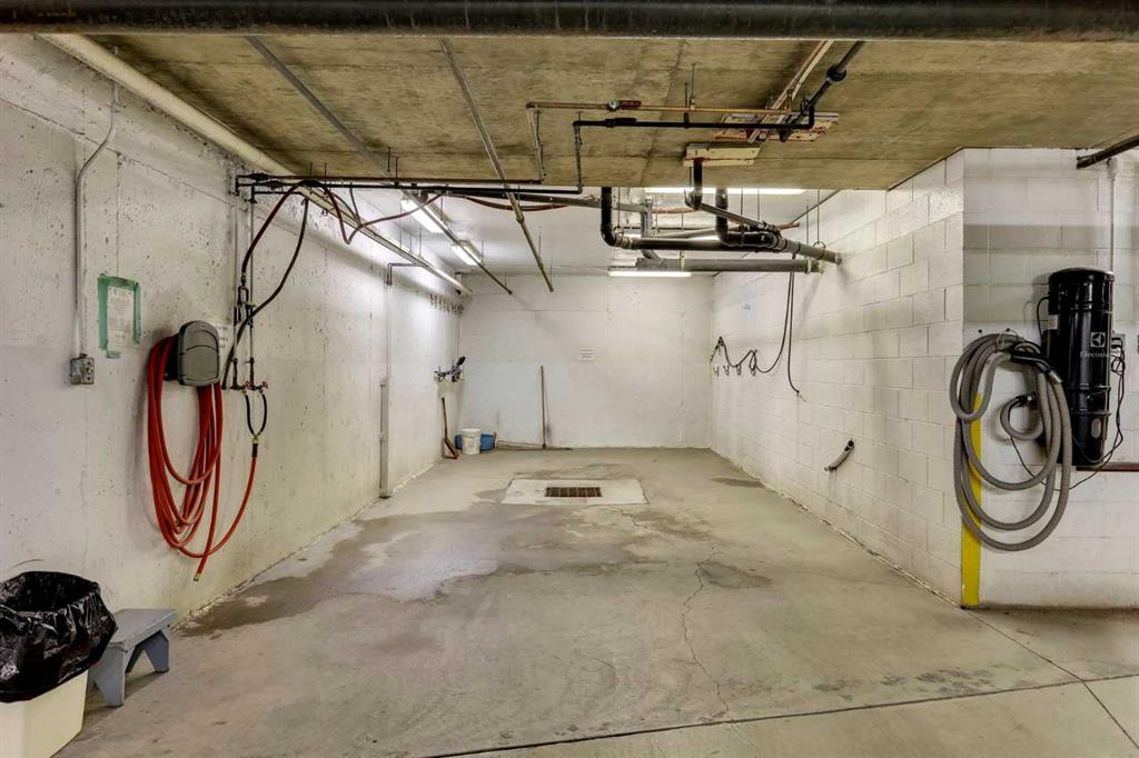 Underground garage wash bay with wall-mounted hoses and a central floor drain.