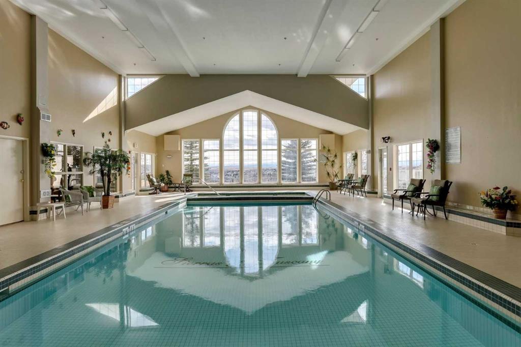 Indoor pool with turquoise water and a tall arched window overlooking the landscape.