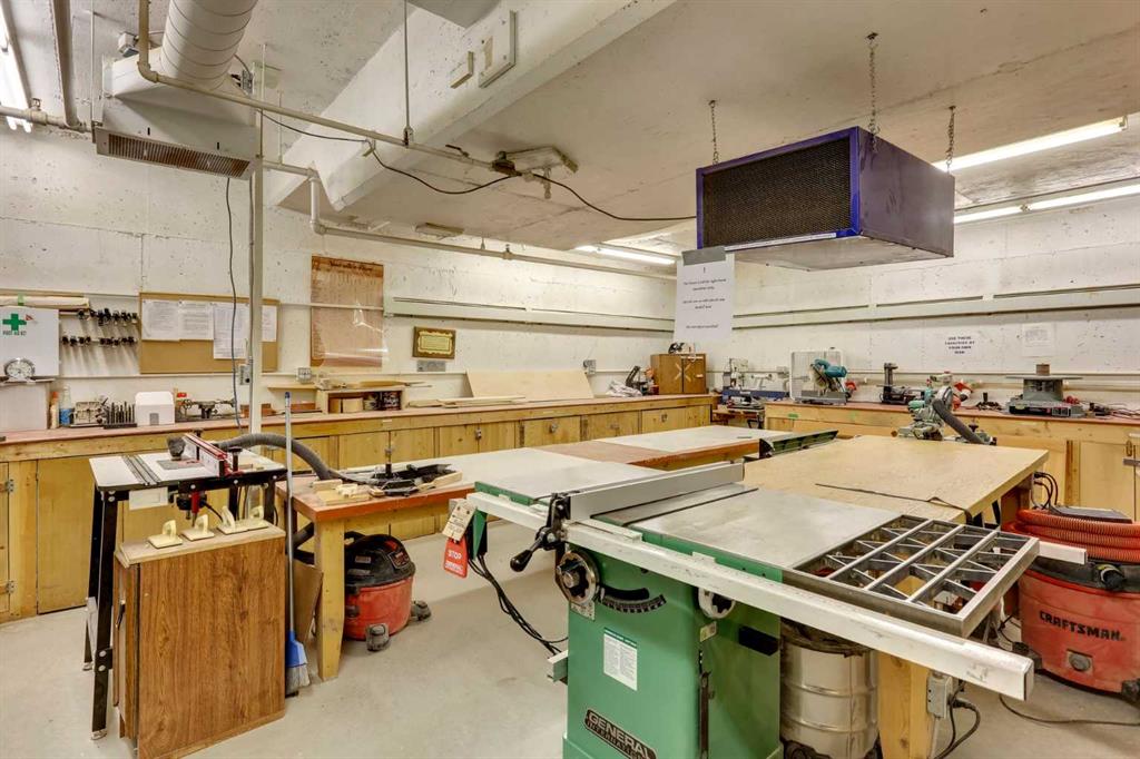 Woodworking workshop with workbenches, a green table saw, and dust-collection equipment.