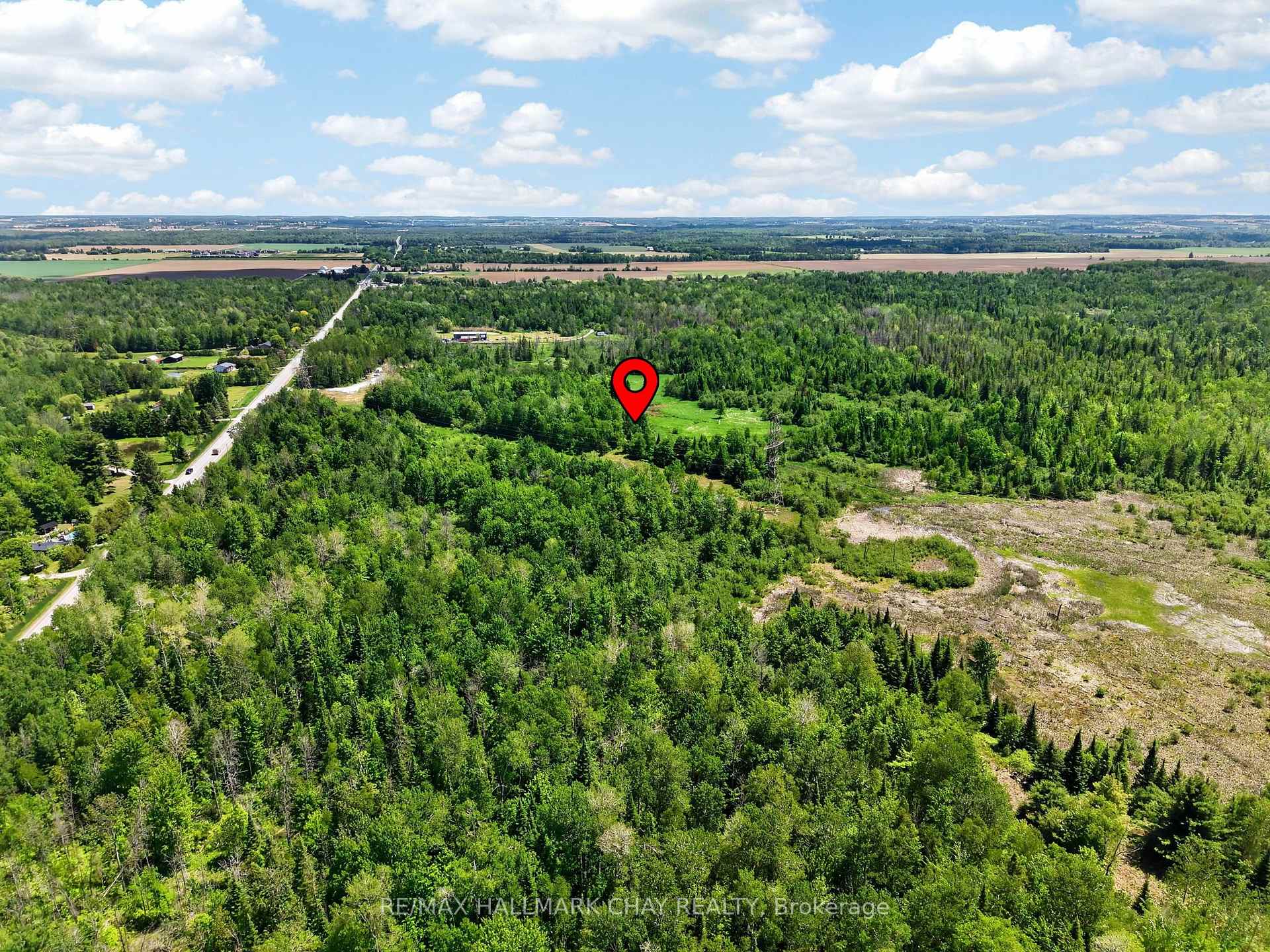 Aerial view of wooded rural land with a clearing marked by a red location pin.
