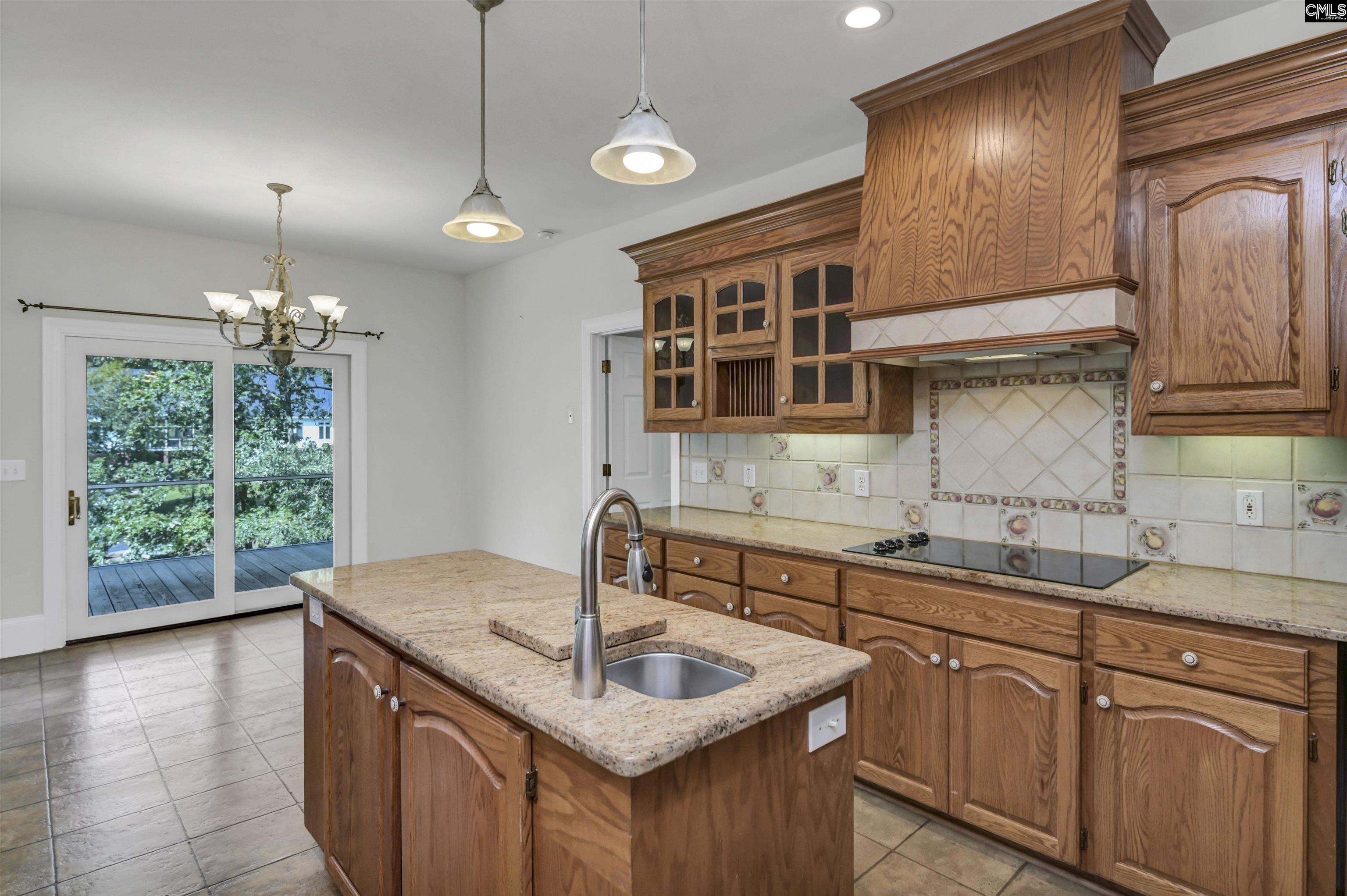 Kitchen with oak cabinetry, granite island, tiled backsplash, and sliding doors to a deck.