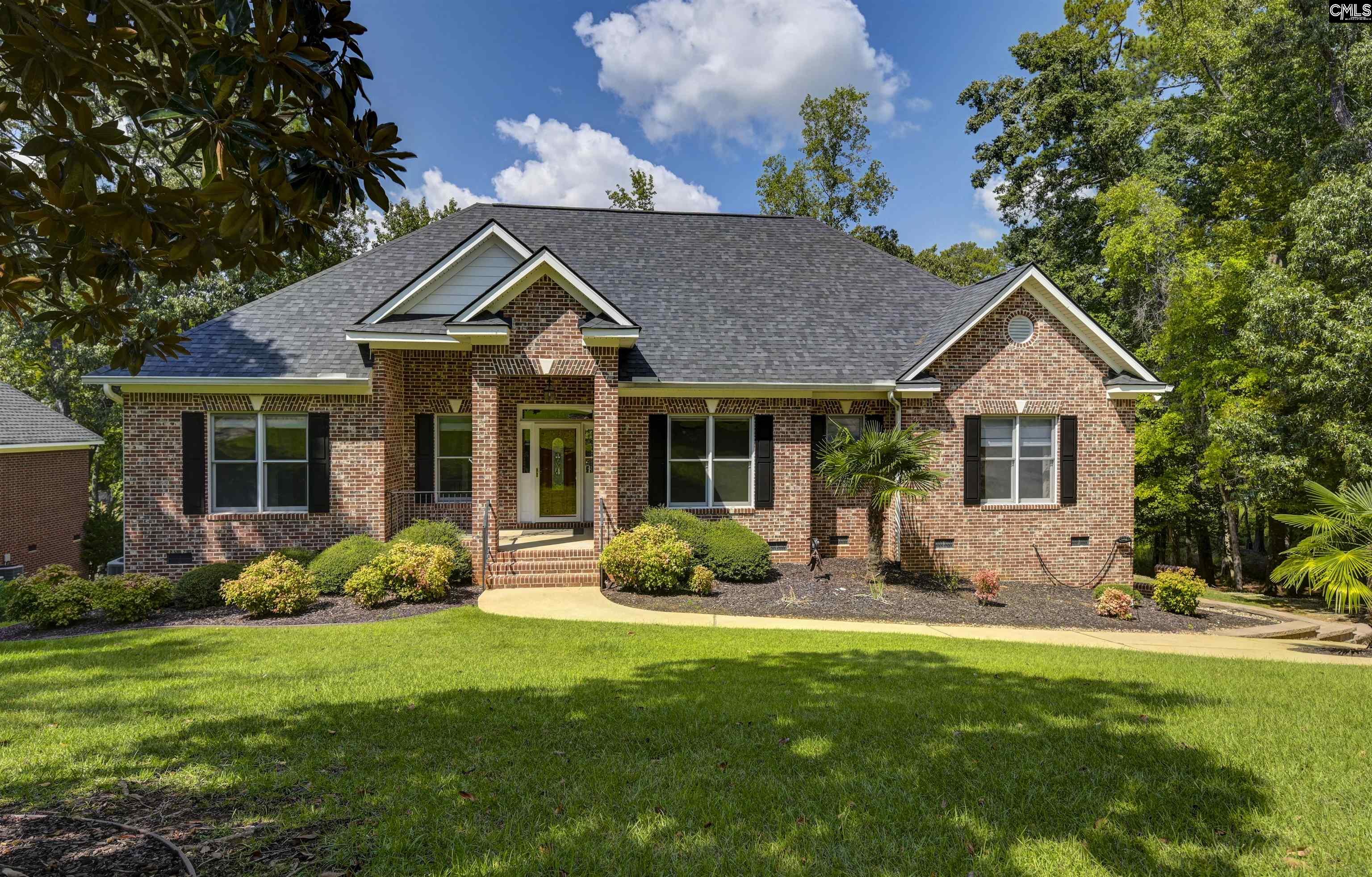 Red brick home with a covered entry, landscaped front yard, and broad green lawn.