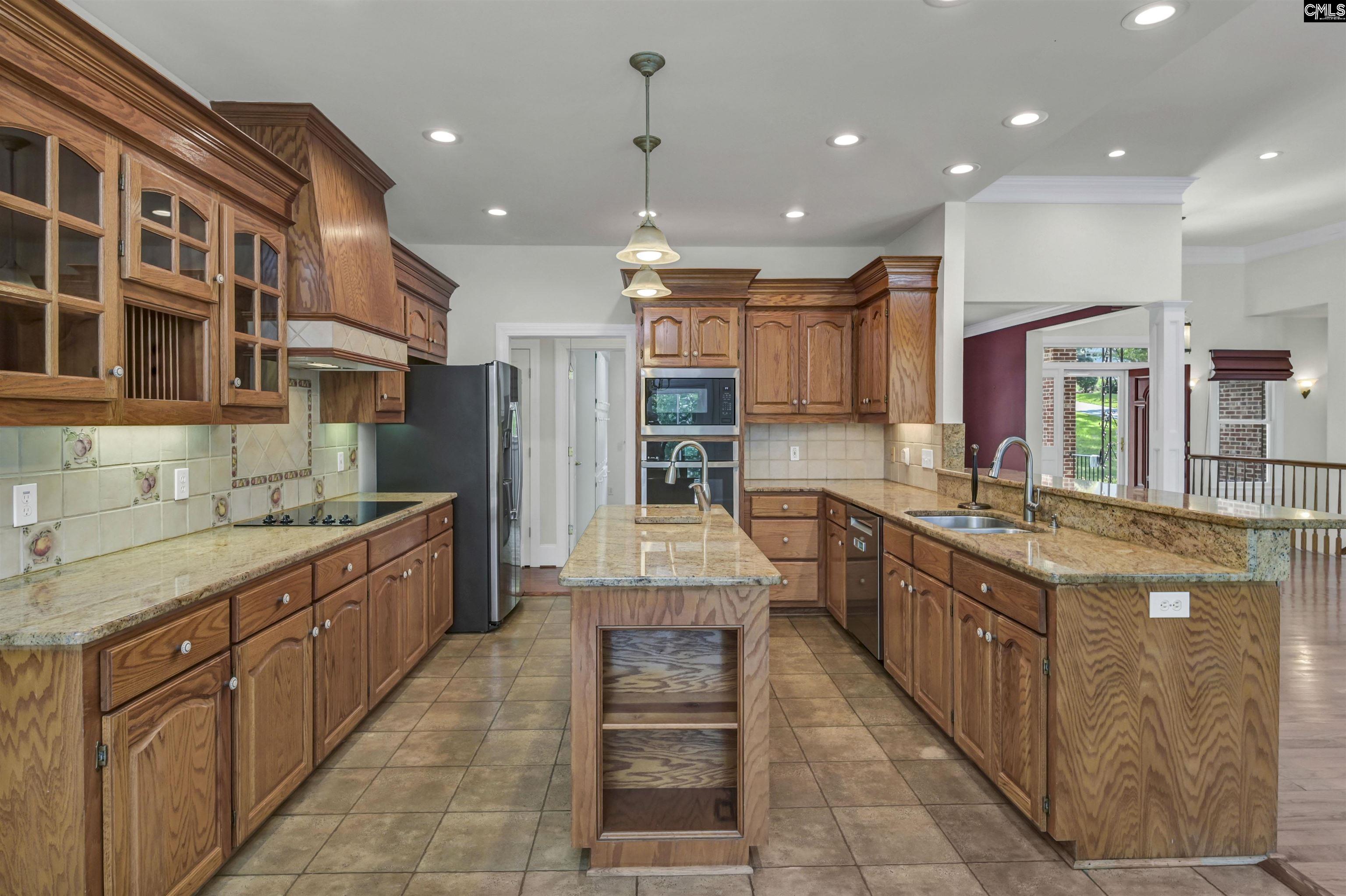 Spacious kitchen with wood cabinetry, granite counters, and a central island.