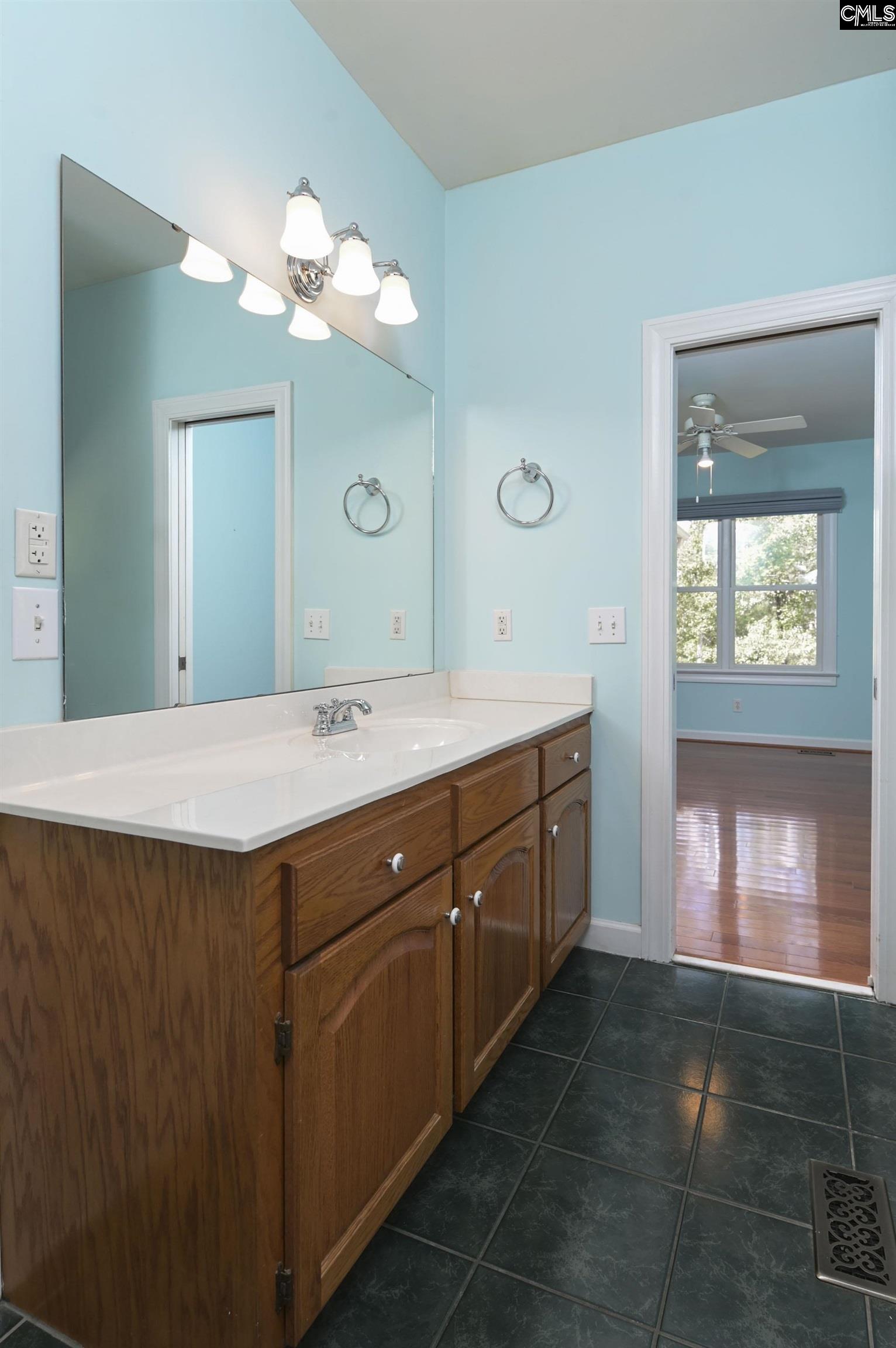 Bathroom vanity with wooden cabinets, a large mirror, and turquoise walls.