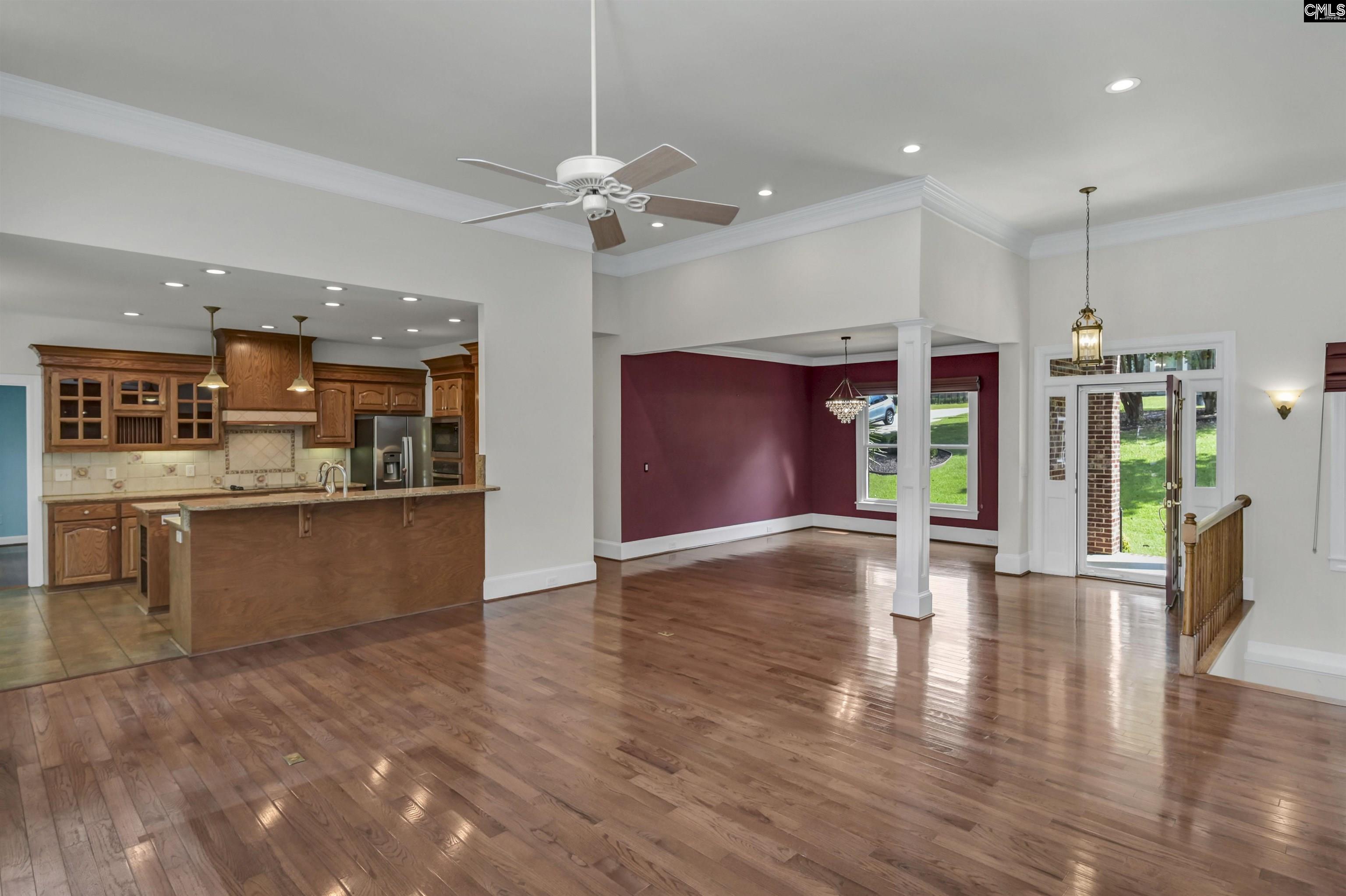Open-plan kitchen and dining area with polished hardwood floors, wood cabinetry, and burgundy walls.