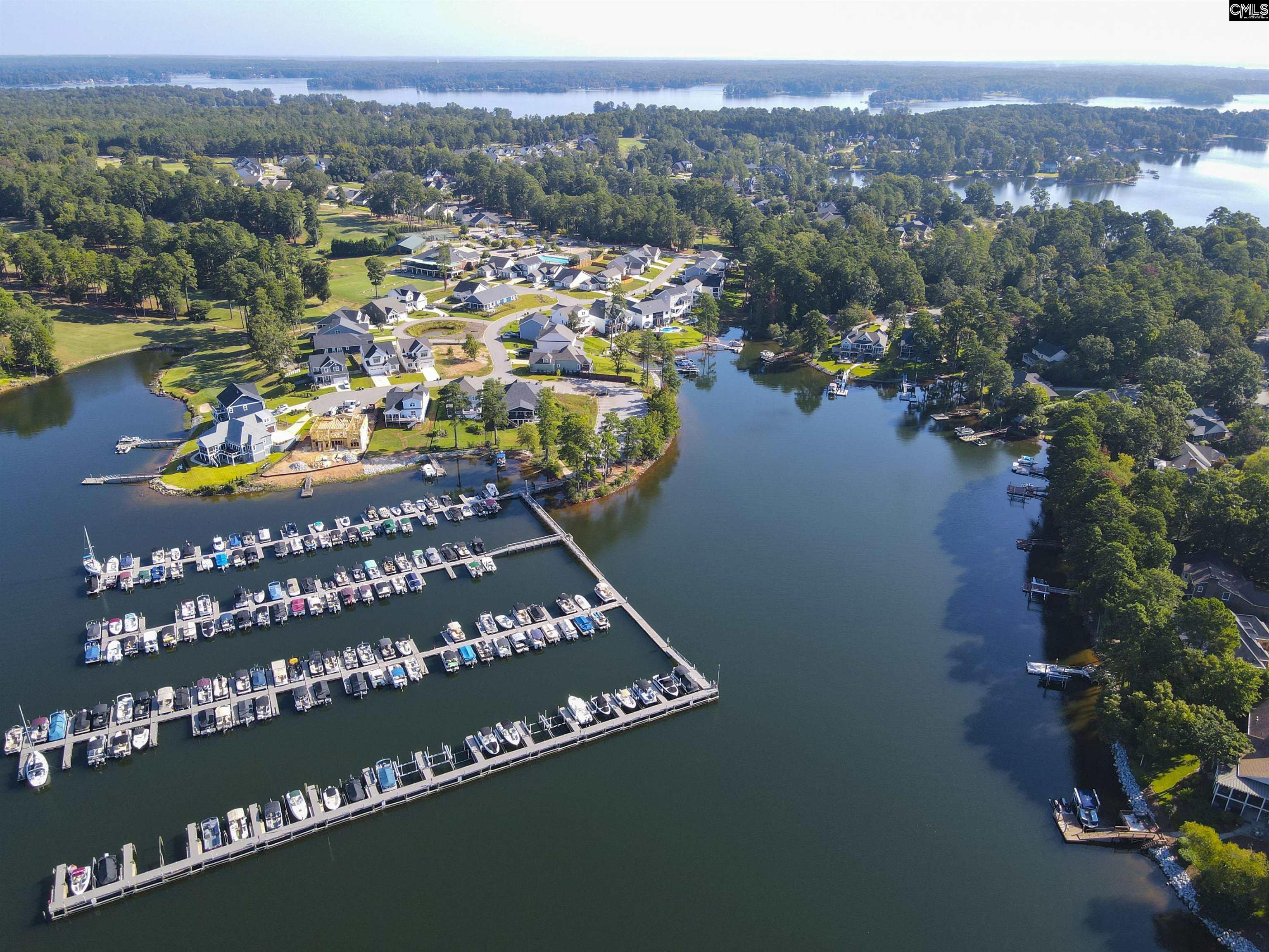 Aerial view of a lakeside neighborhood and marina with rows of boats along the docks.
