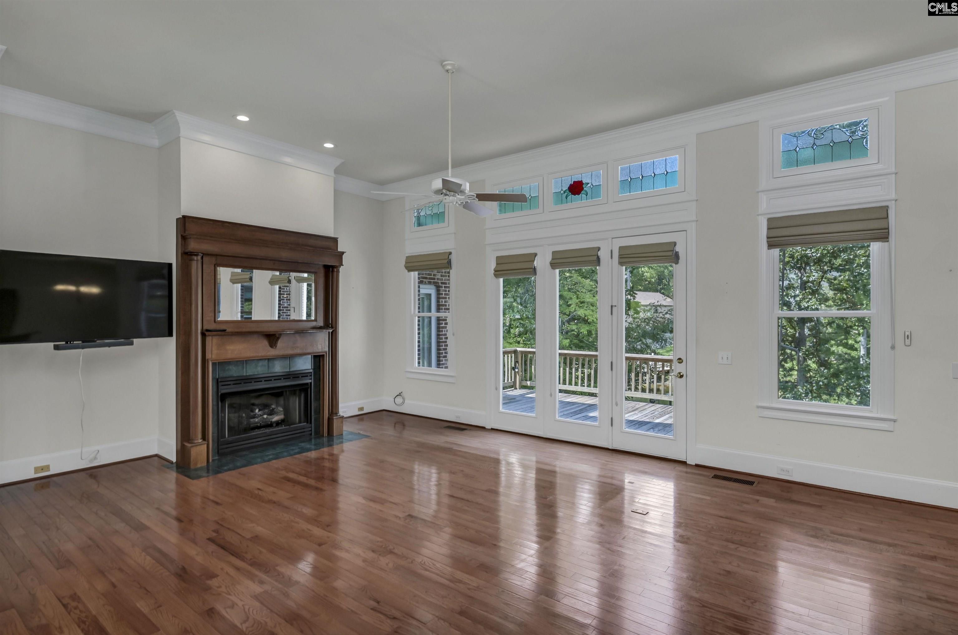 Living room with hardwood floors, a wood-trimmed fireplace, and stained-glass windows above French doors.