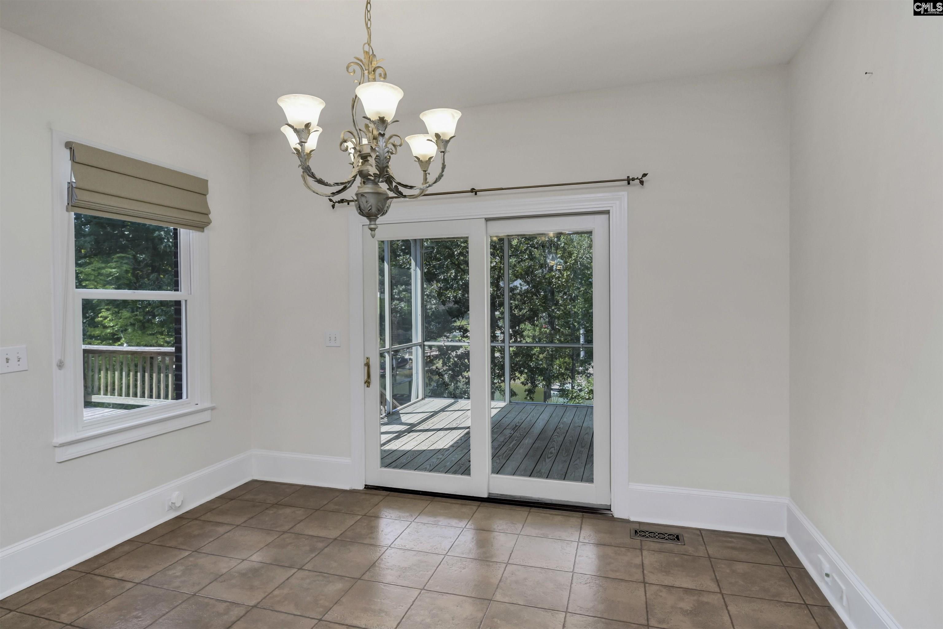 Empty dining room with tile flooring, a chandelier, and sliding glass doors to a deck.
