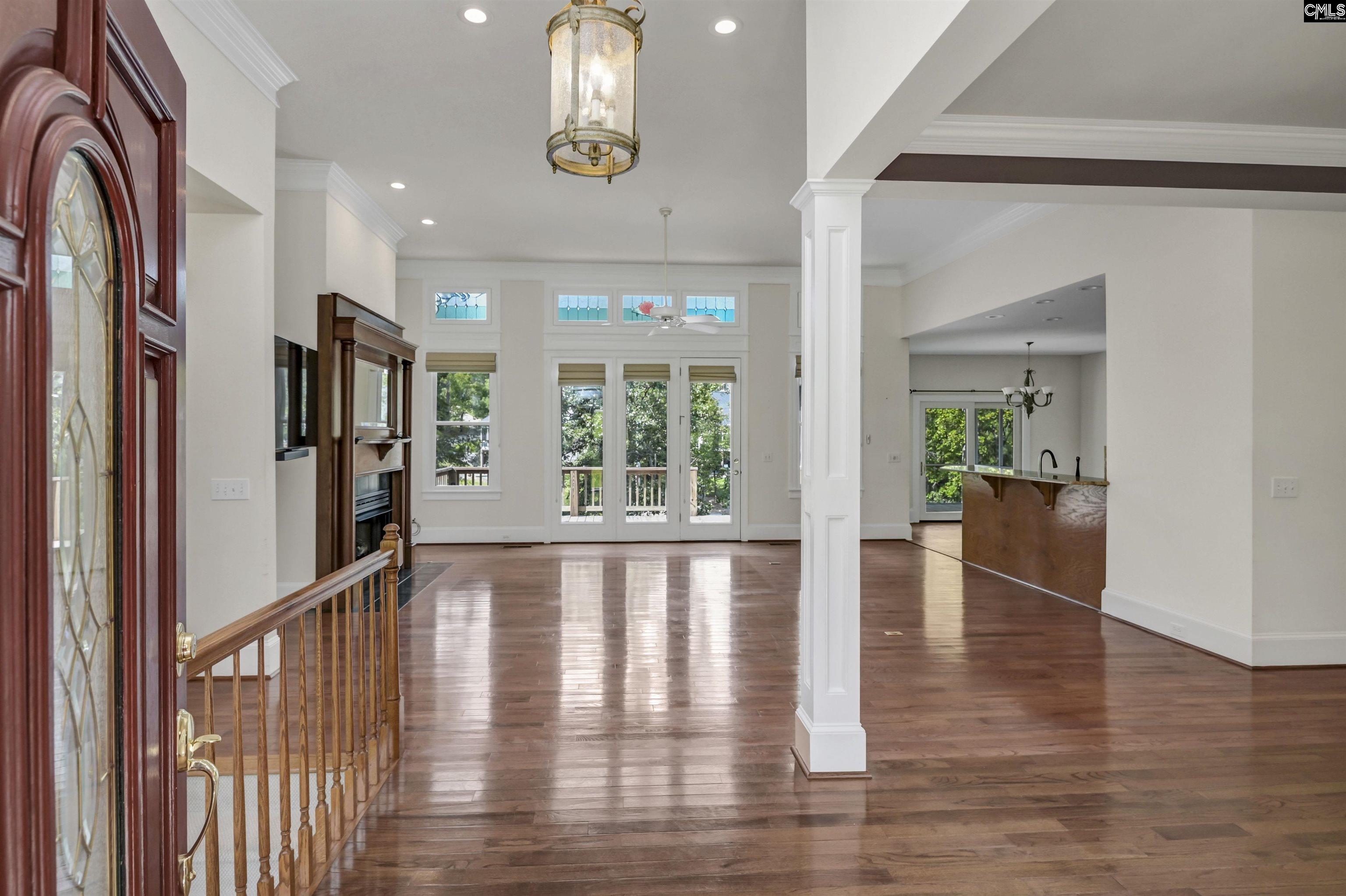 Open-plan foyer and living area with hardwood floors, a fireplace, and tall windows.