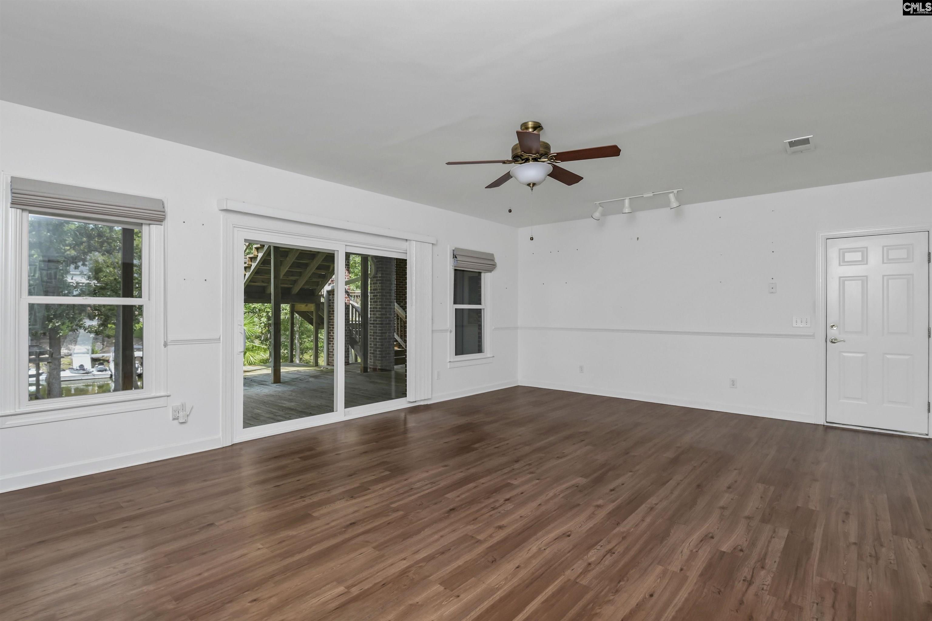 Unfurnished living room with wide-plank wood floors and sliding doors to a covered deck.