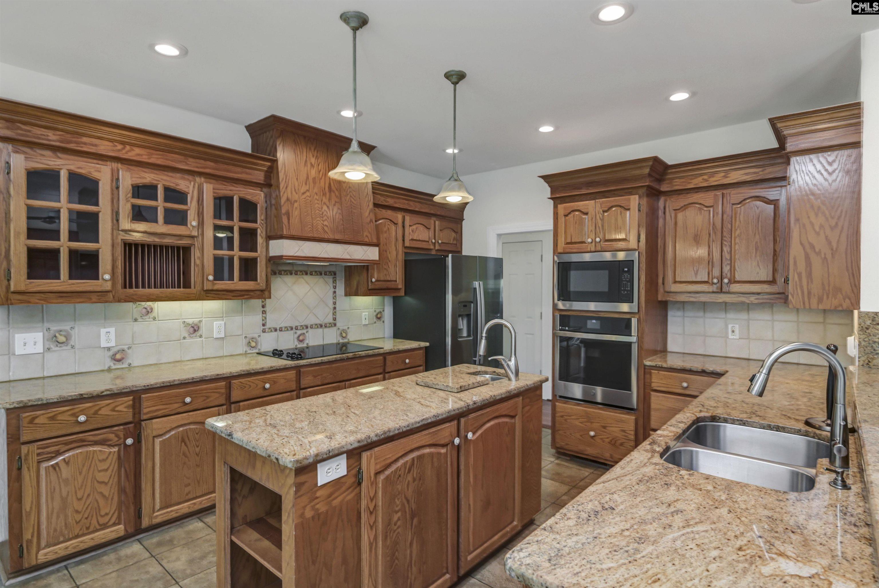 Kitchen with warm wood cabinetry, granite countertops, a central island, and stainless steel appliances.