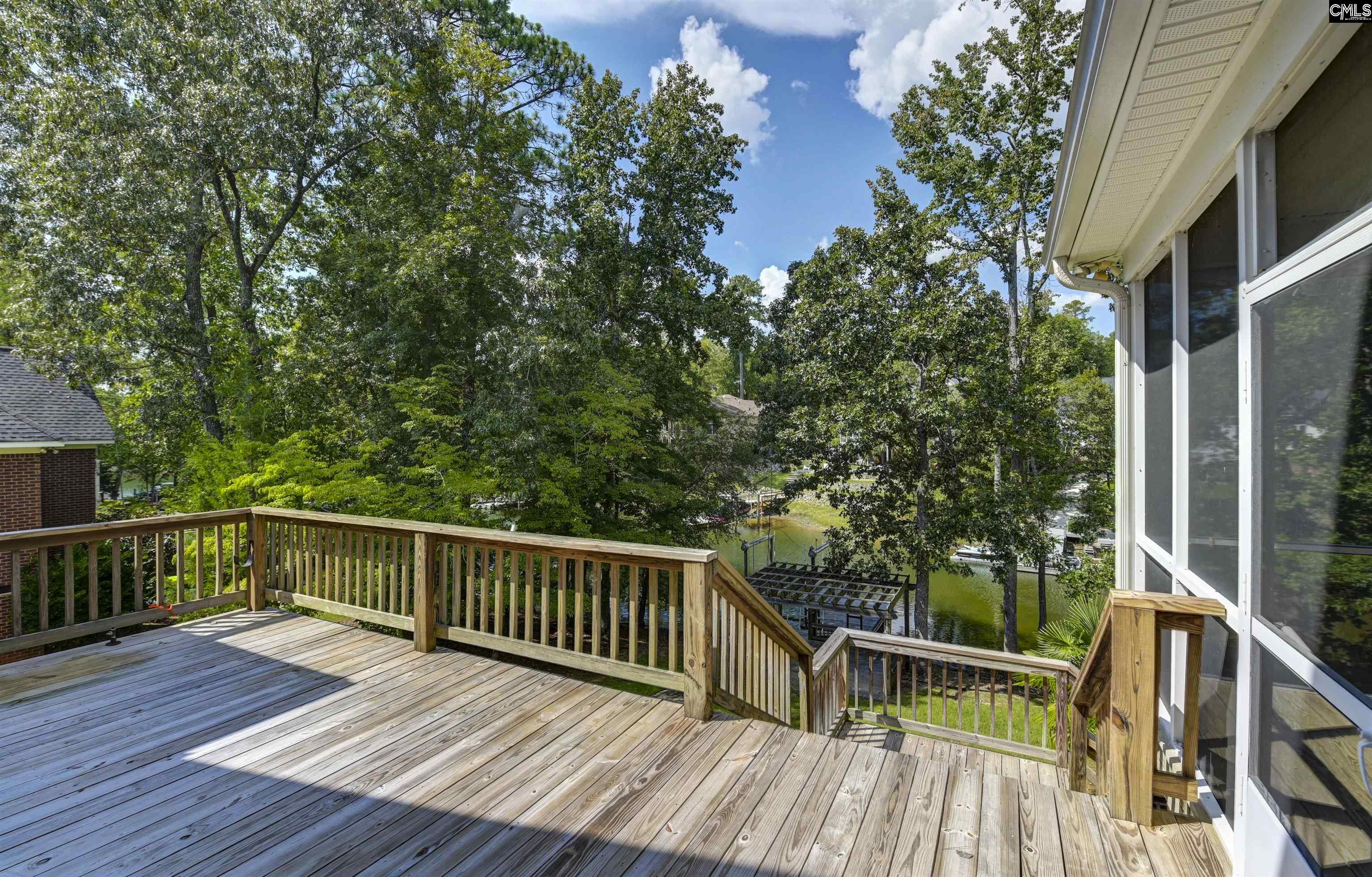 Wooden deck overlooking a tree-lined waterfront and docks.