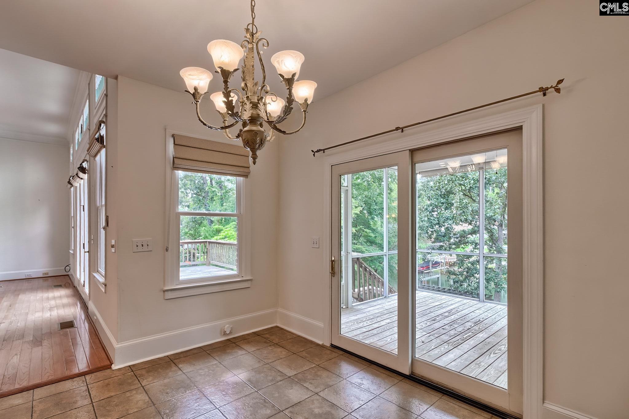 Dining area with tile flooring, a chandelier, and sliding doors to a deck.