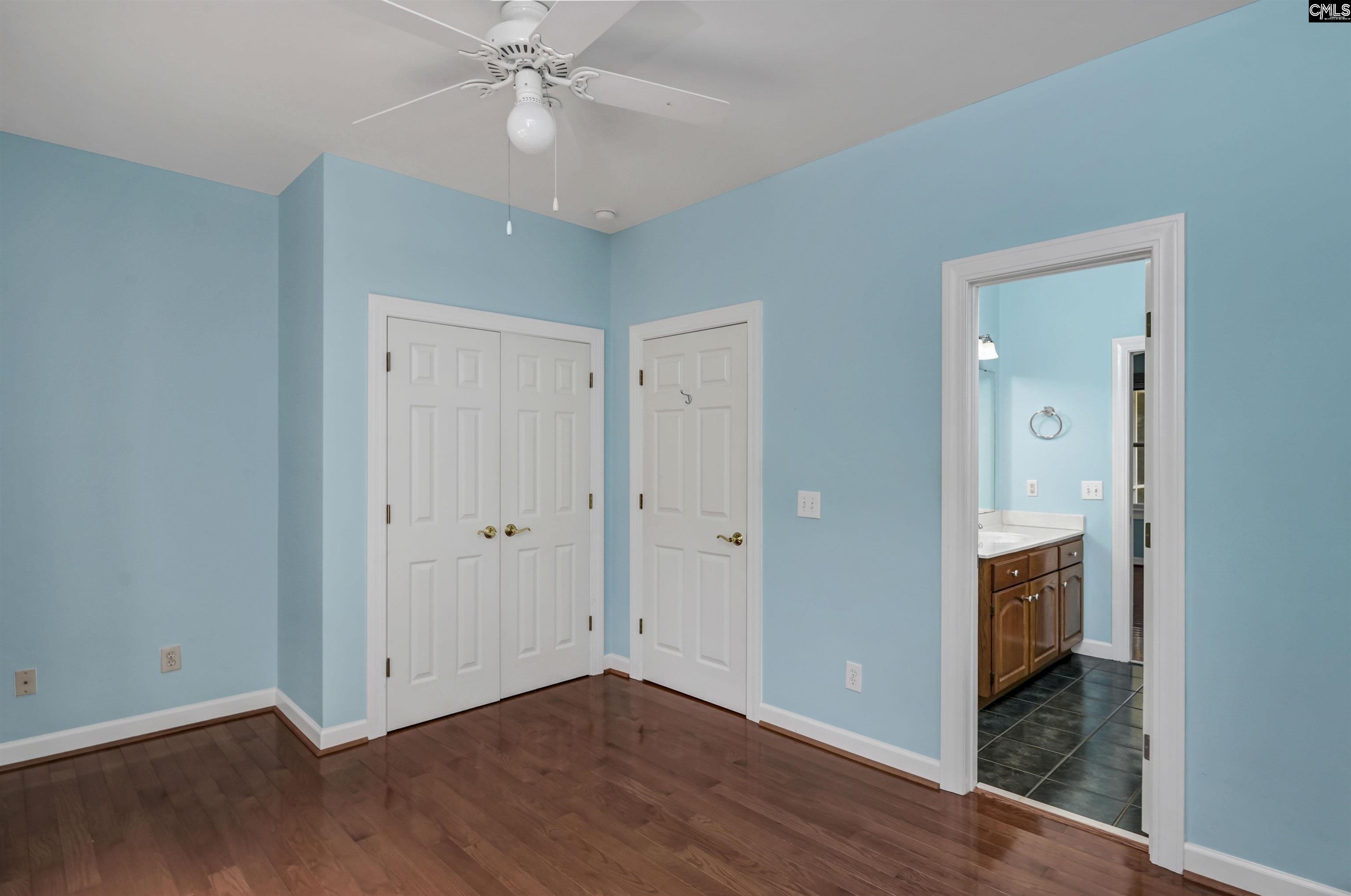 Unfurnished blue bedroom with hardwood floors, double closets, and an adjoining bathroom.