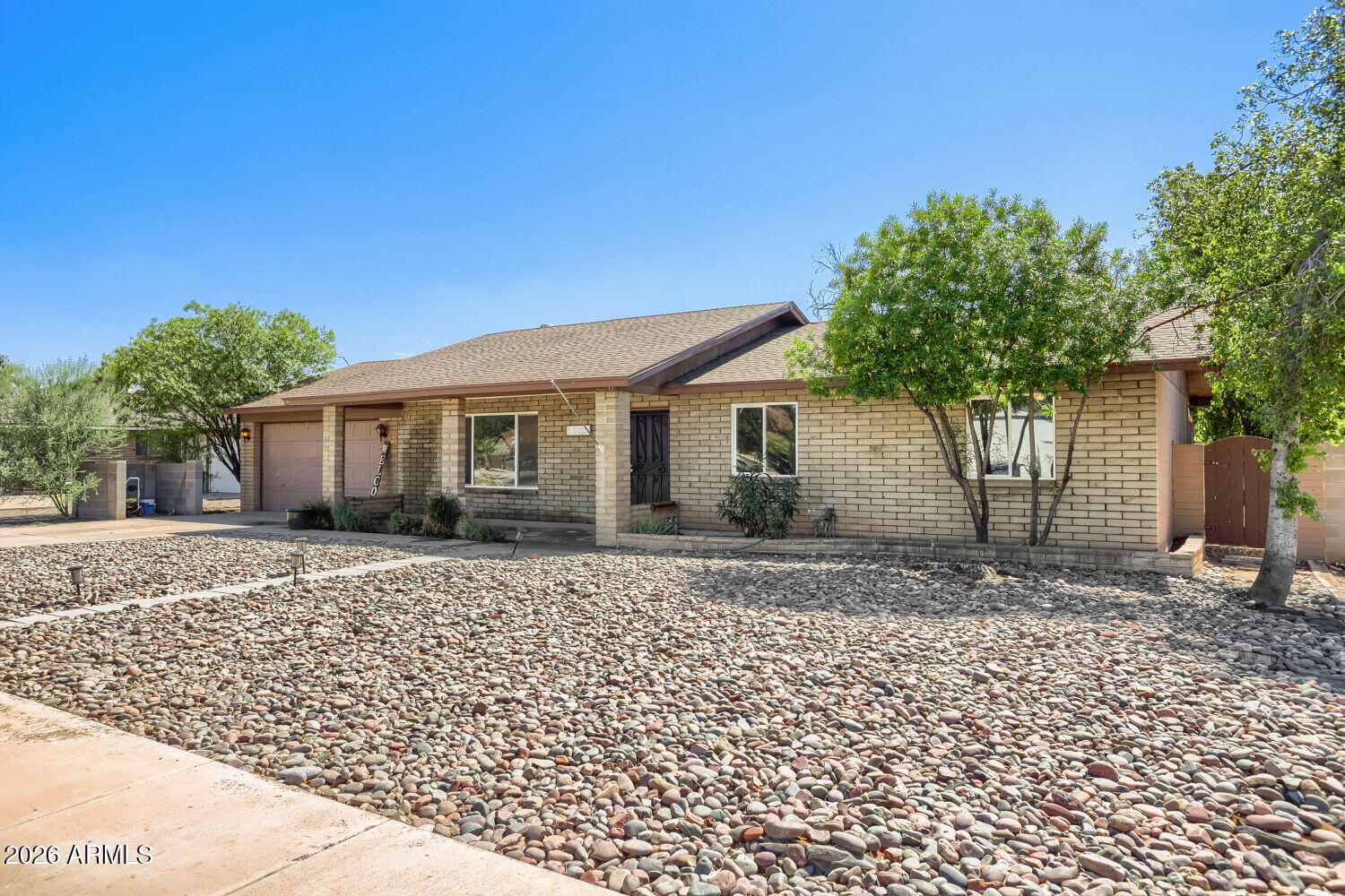 Single-story brick home with an attached garage and rock landscaping across the front yard.