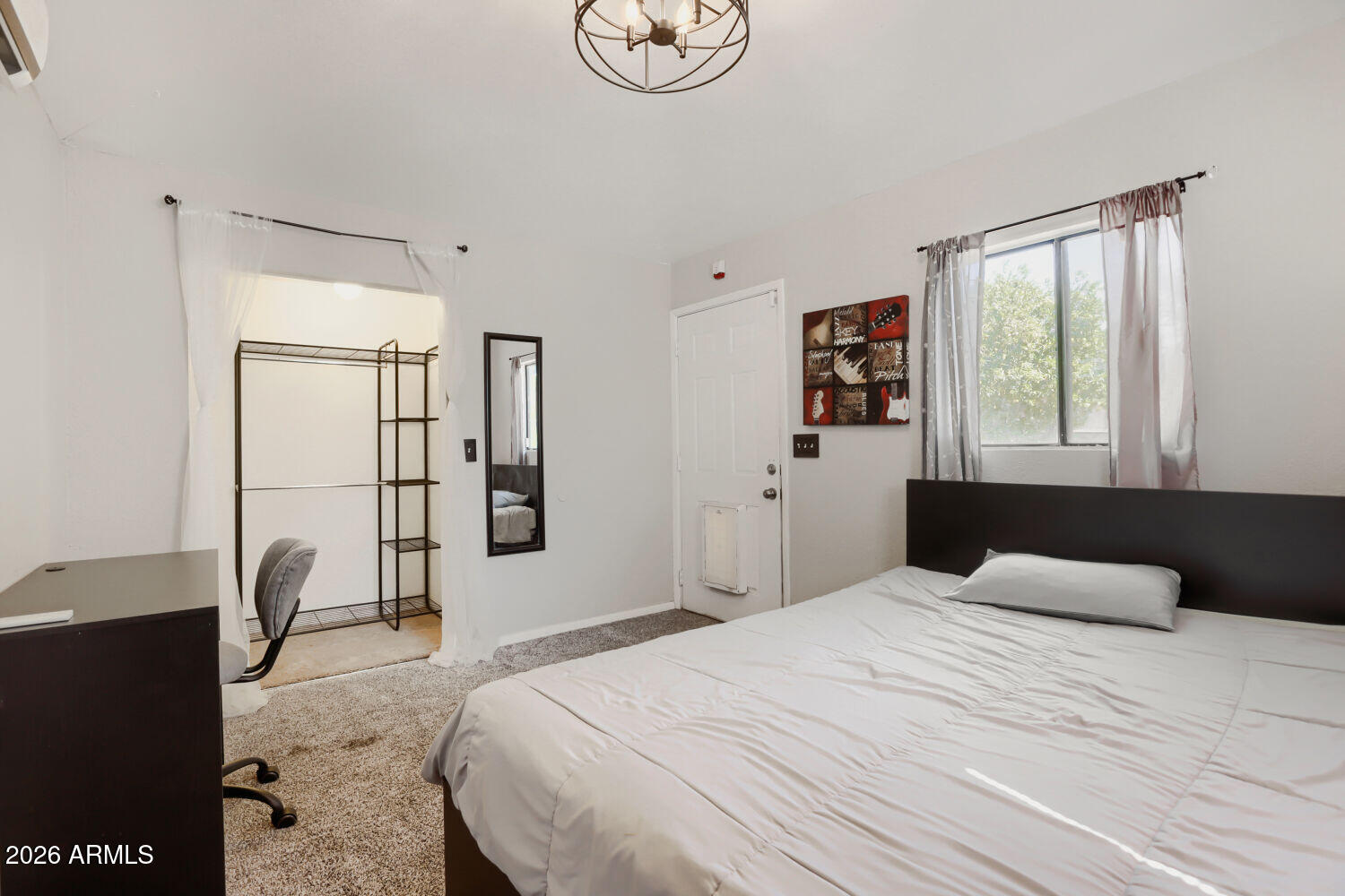 Bedroom with a large bed, dark headboard, and curtained closet area with open shelving.