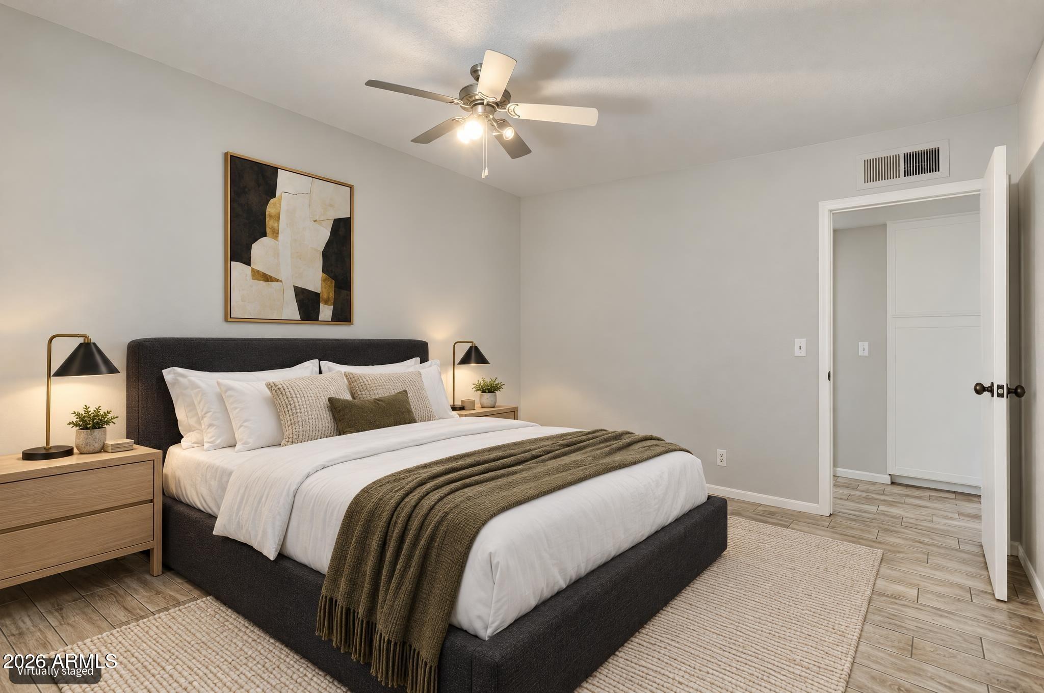 Virtually staged bedroom with a dark bed, white bedding, olive throw, and open closet doorway.