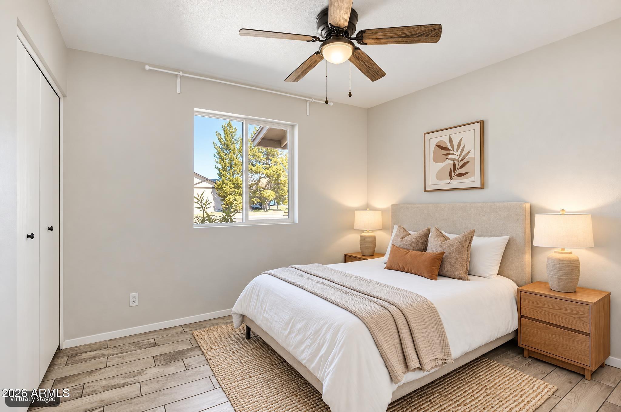 Virtually staged bedroom with a white bed, wood nightstands, and a ceiling fan.