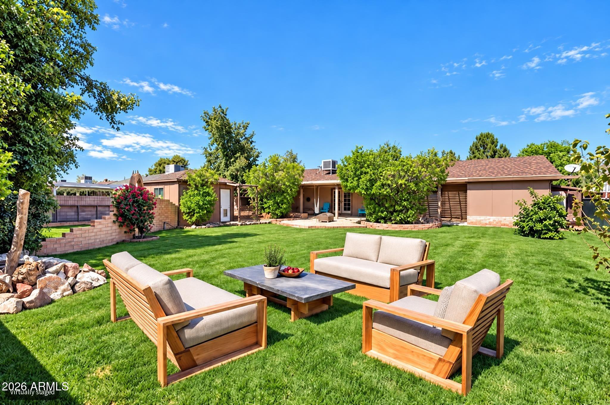 Backyard lawn with staged outdoor seating and a covered patio behind the house.