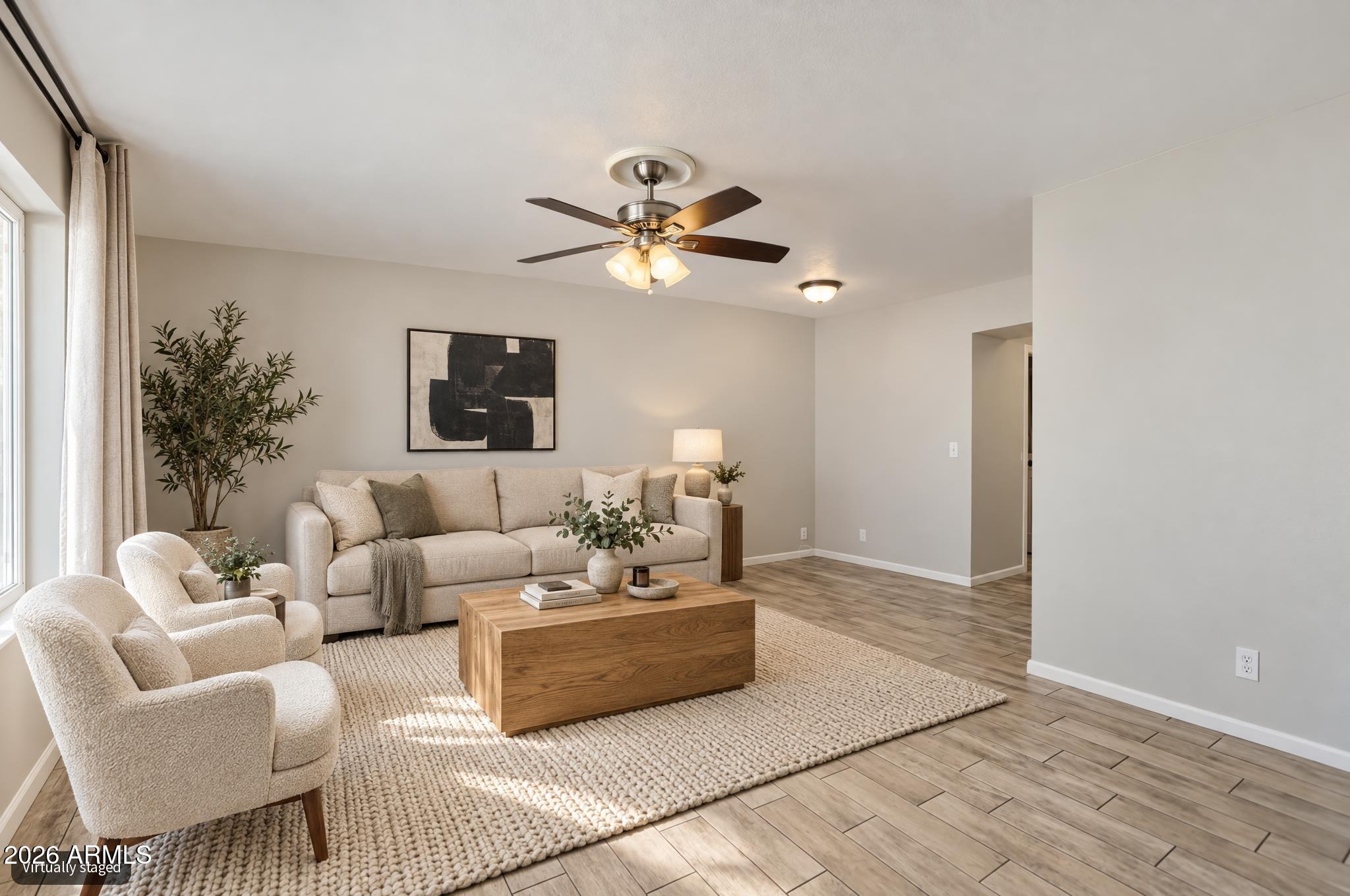 Staged living room with beige seating, a wood coffee table, and a large woven rug.