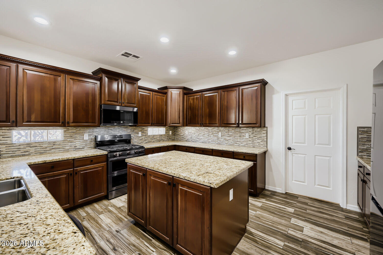 Kitchen with dark wood cabinets, granite counters, and a large central island.