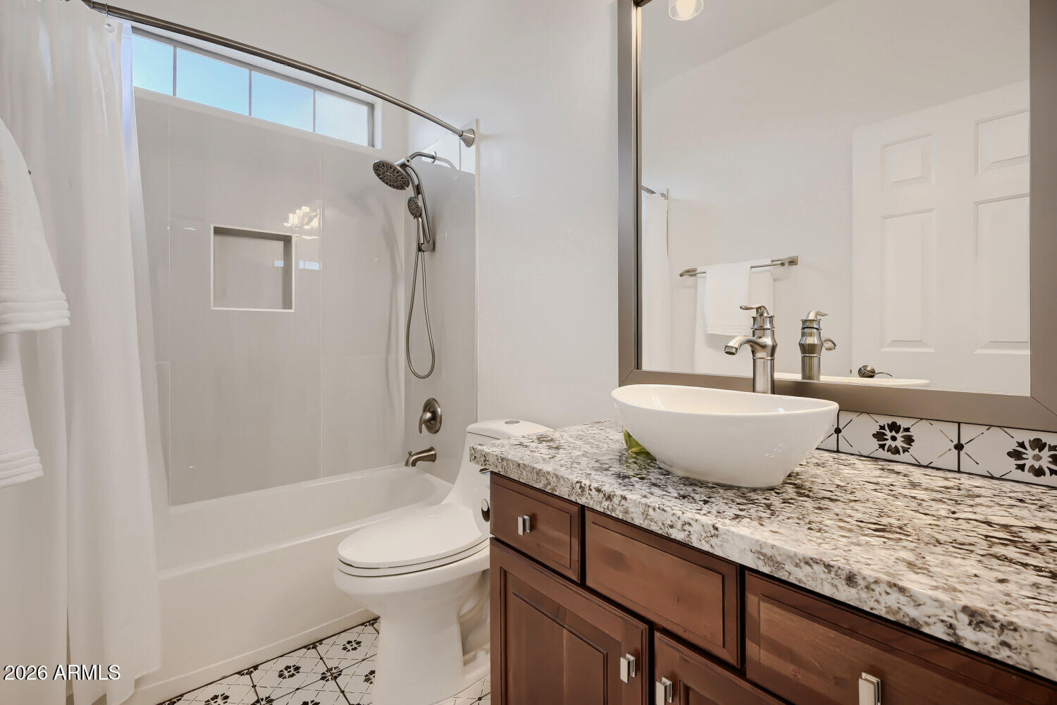 Bathroom with a tub-shower, high window, and granite-topped vanity with a white vessel sink.