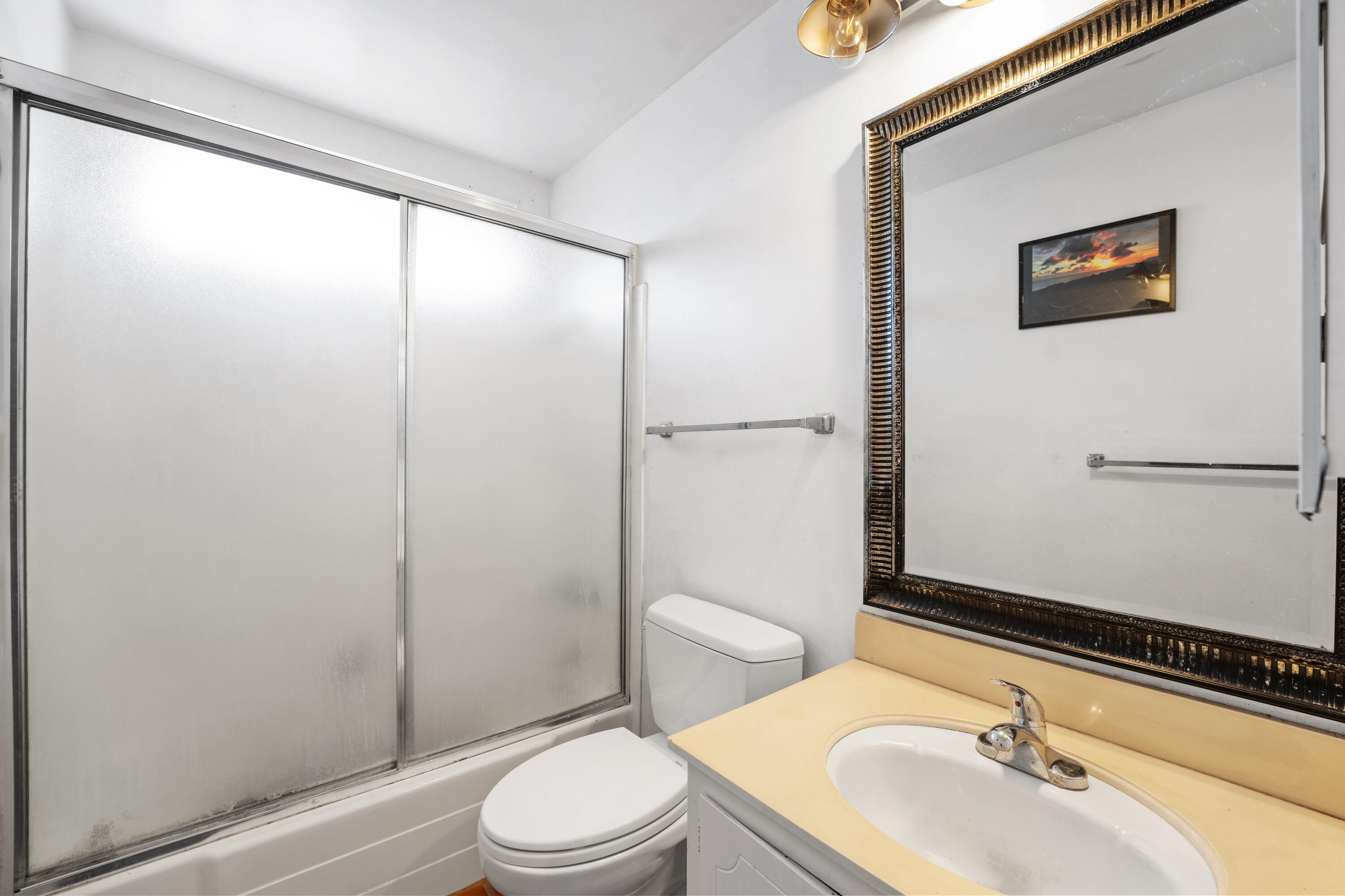 Bathroom with a frosted-glass shower enclosure and a large ornate framed mirror.