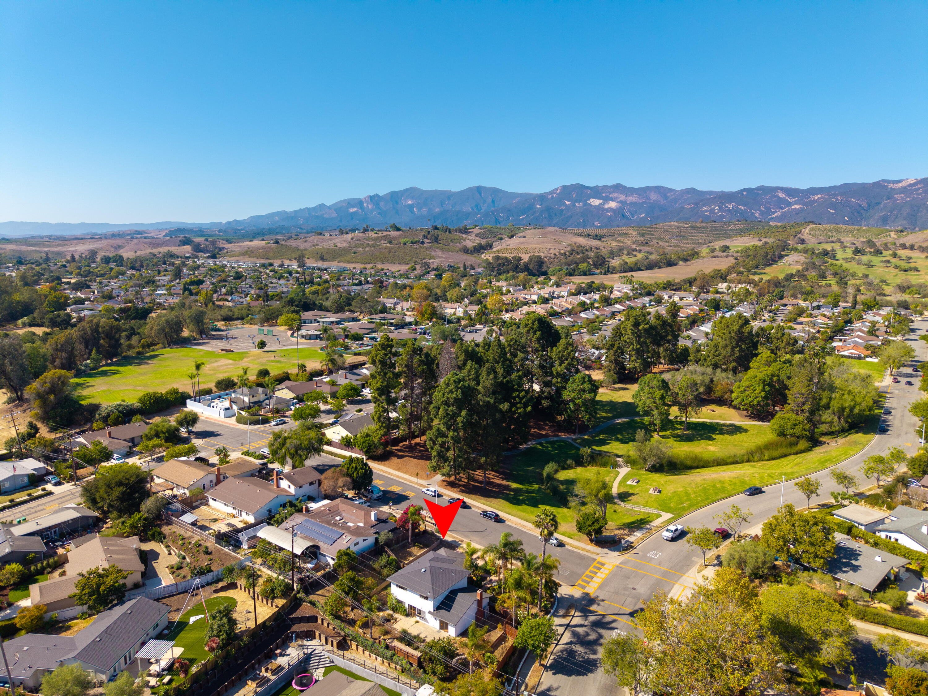 Aerial neighborhood view of 7360 Padova Drive, marked by a red arrow, with the Santa Ynez Mountains beyond.